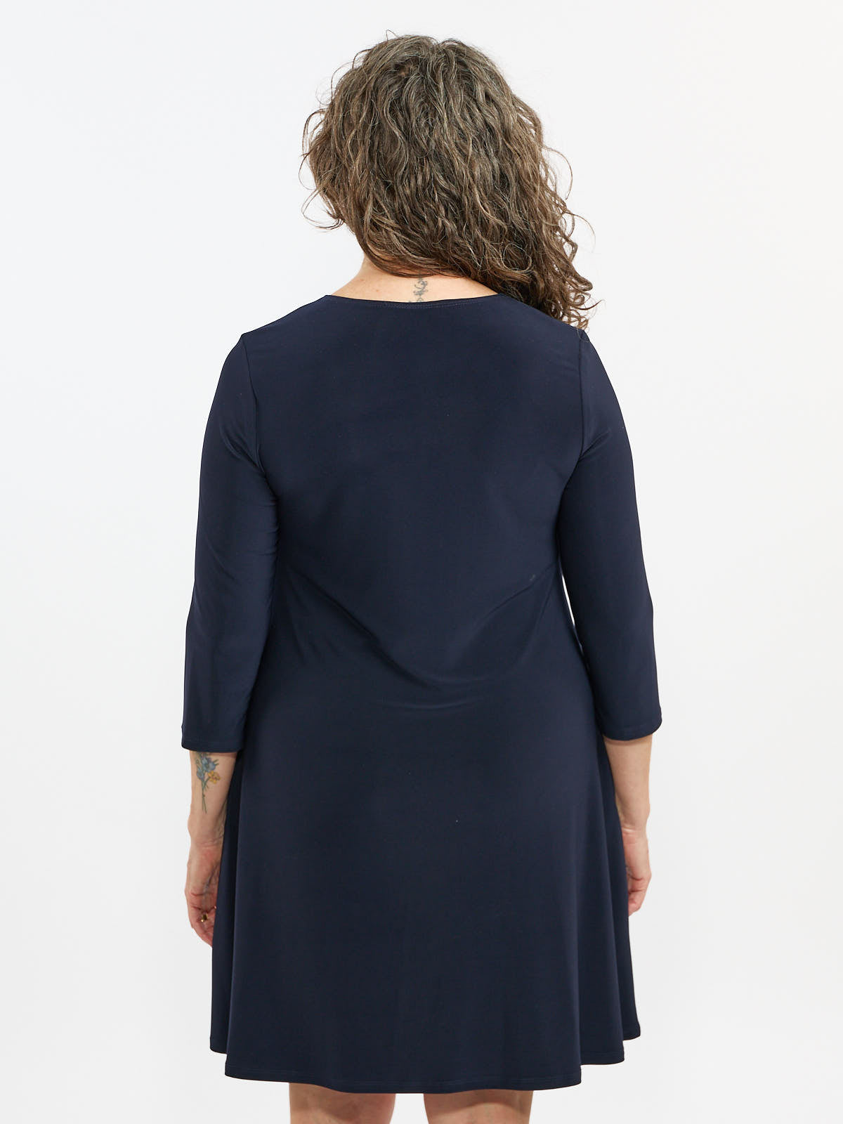 Back view of a navy blue, knee-length dress with three-quarter sleeves on a light background.