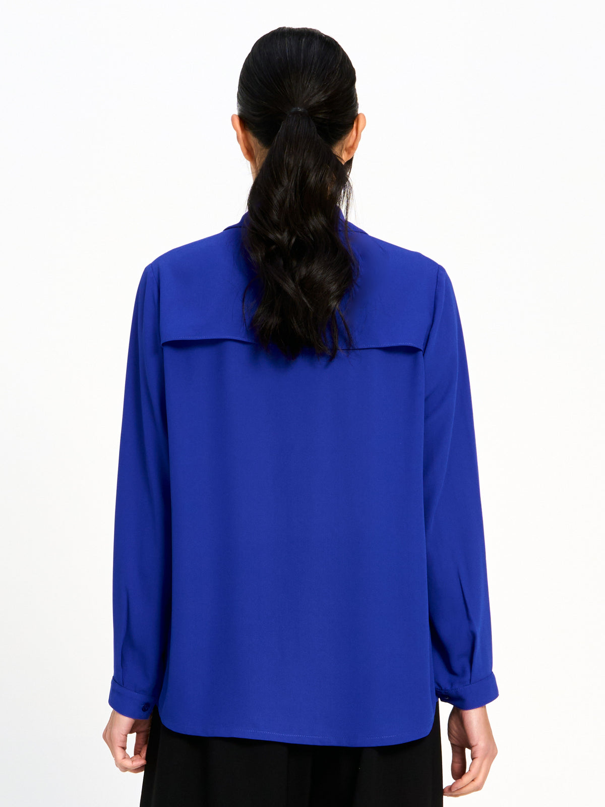 Back view of a long-sleeve cobalt blue top with a yoke detail across the upper back.