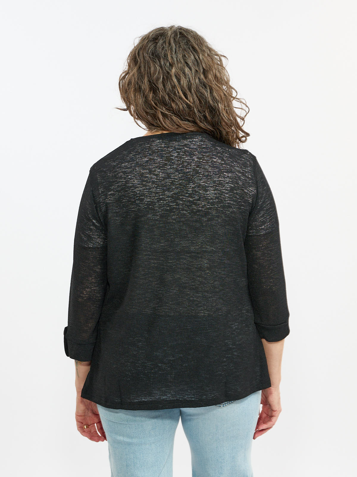 Back view of a long-sleeve black semi-sheer top paired with light blue denim jeans against a white background.