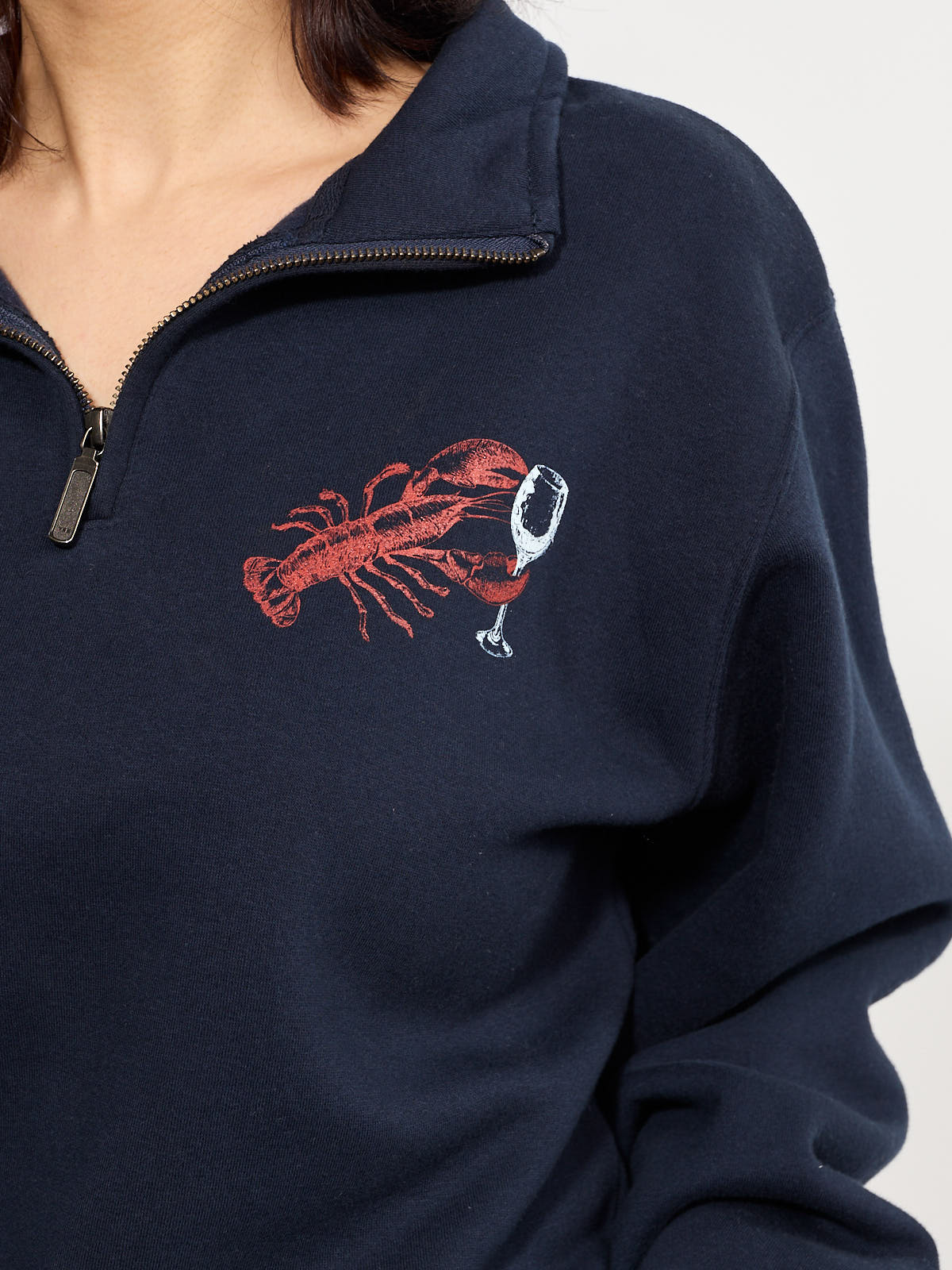 Navy quarter-zip sweater with lobster and wine glass graphic on the chest and soft fabric texture.