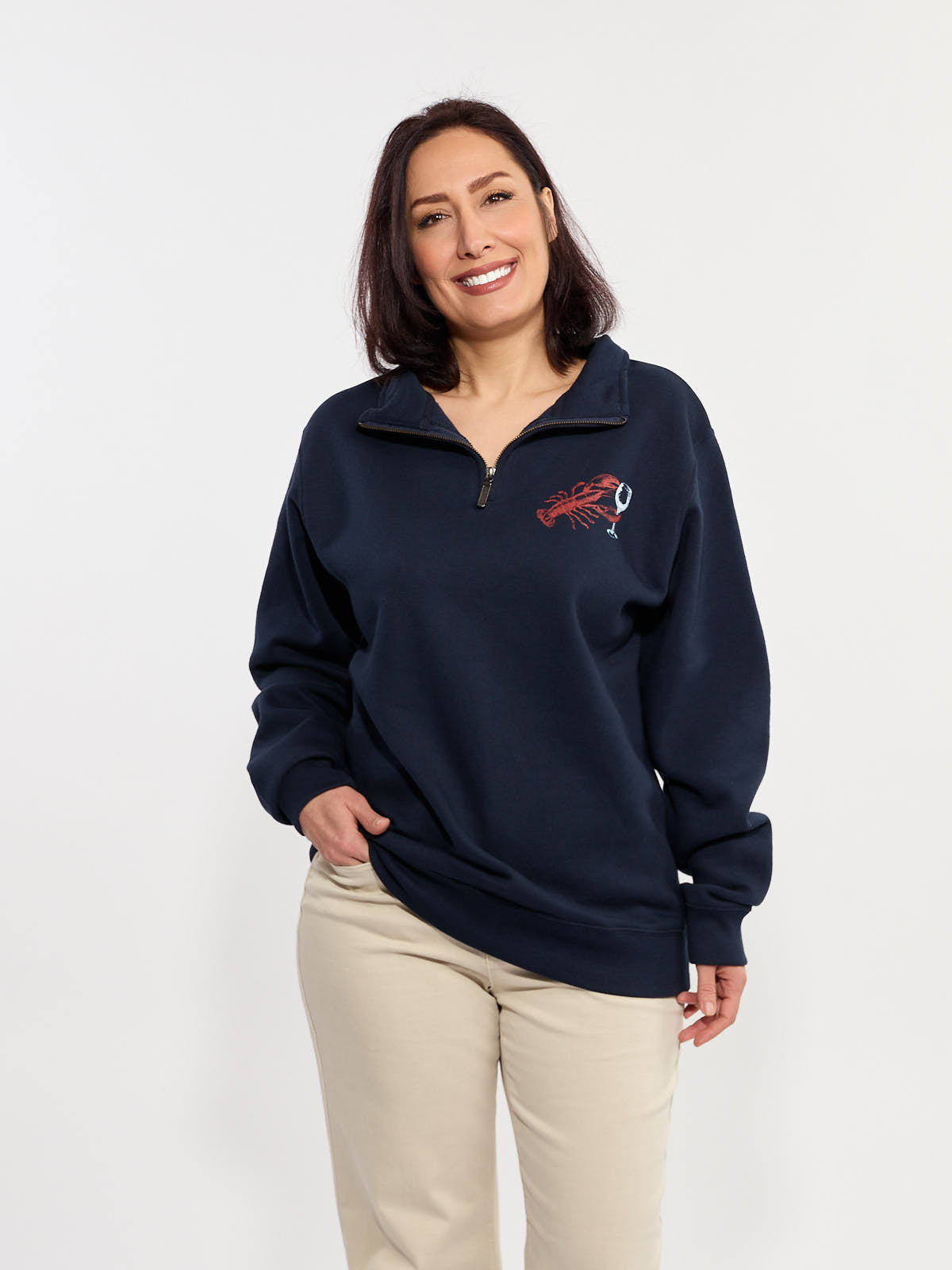 Navy quarter-zip sweatshirt with lobster and wine glass embroidery paired with light beige pants on a plain background.