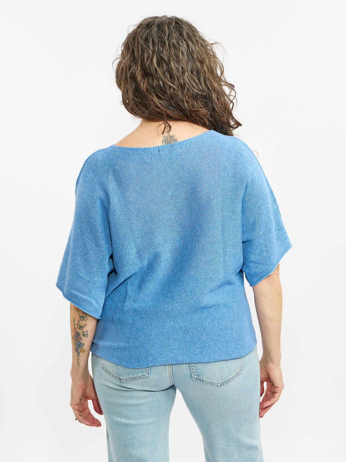 Back view of a light blue Pop Me Over Oversized 3/4 Sleeve Knit Top by Plum Loco in a textured knit fabric.