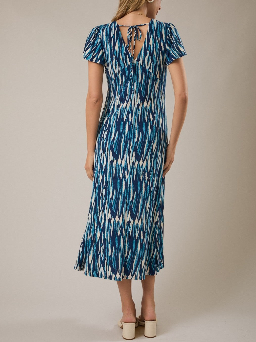 Blue and white patterned midi dress with short sleeves and tie detail at the back neckline