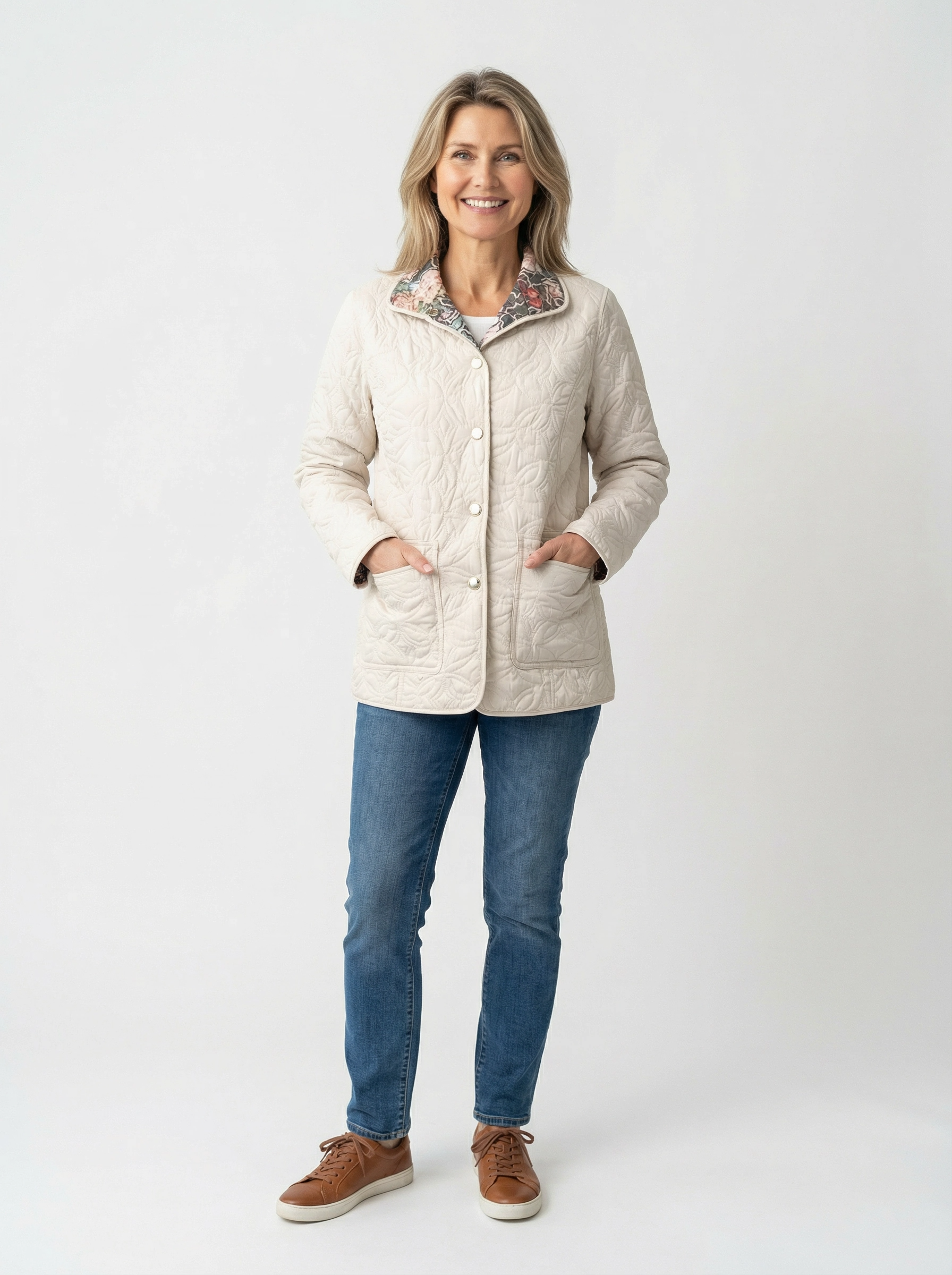 Light cream quilted jacket with floral collar detail paired with blue jeans and brown sneakers on a plain background.