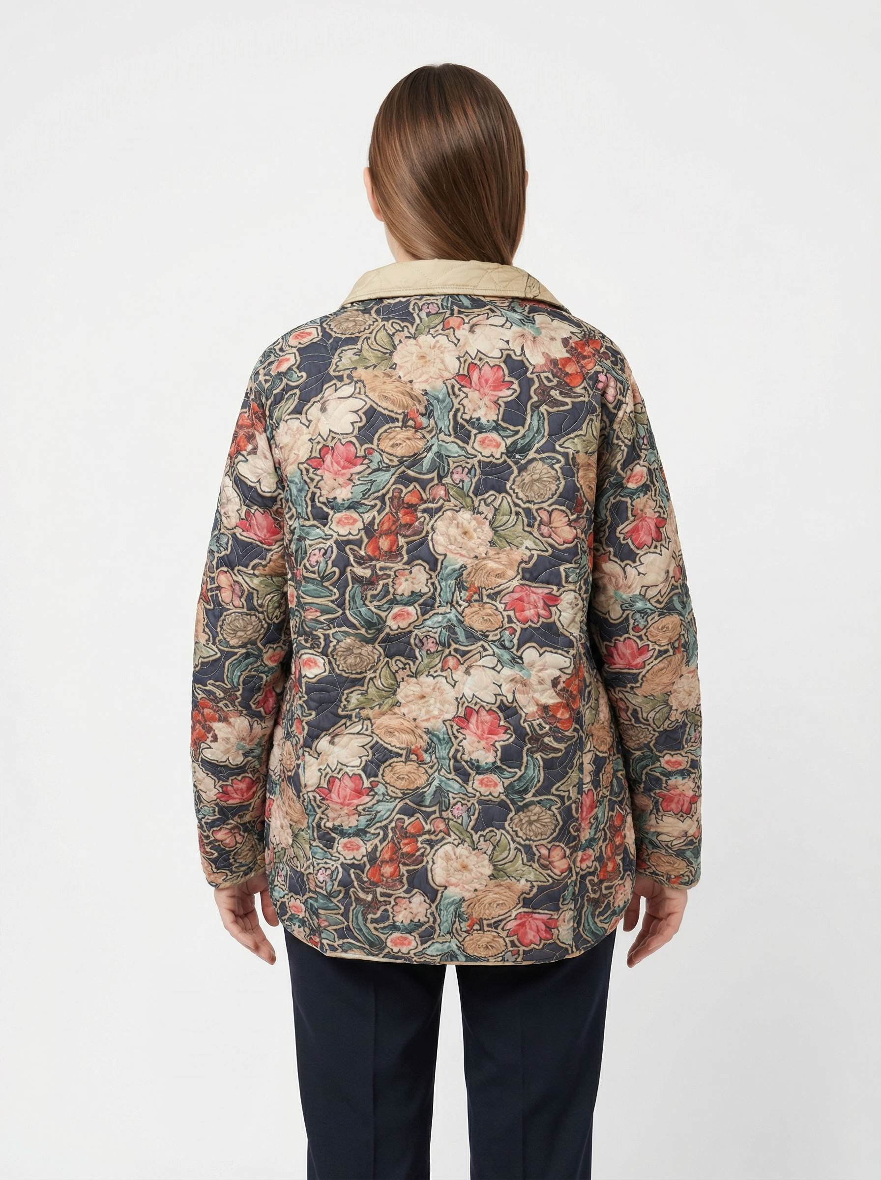 Quilted jacket with multicolor floral pattern and beige collar worn with dark pants viewed from the back.