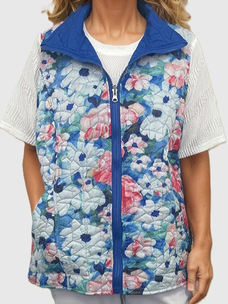 Quilted sleeveless jacket with blue collar and multicolored floral pattern over white textured short sleeve top.