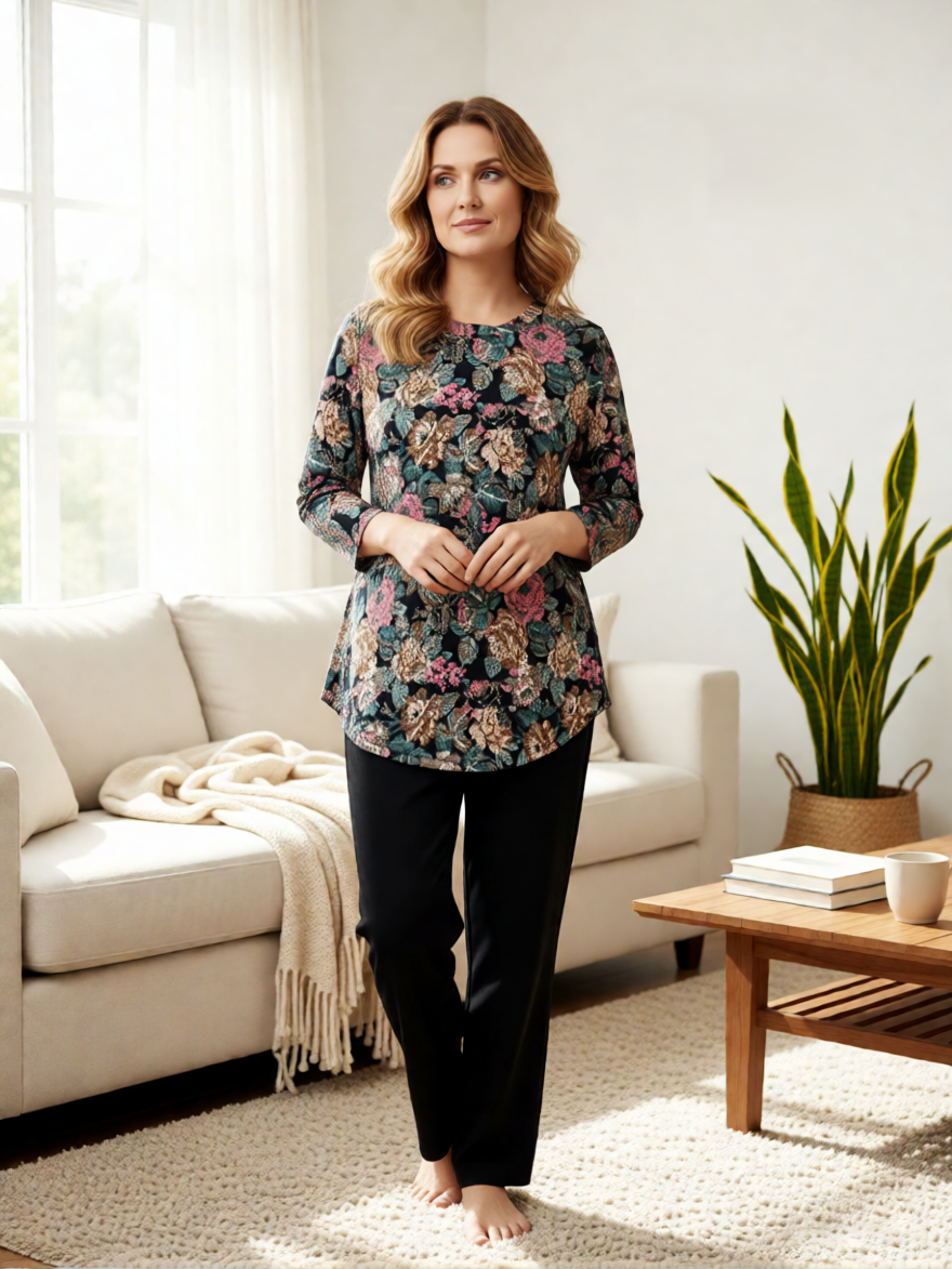 Uneven Hem Printed Hacci Top by Creations with floral pattern, paired with black pants in a bright living room setting.