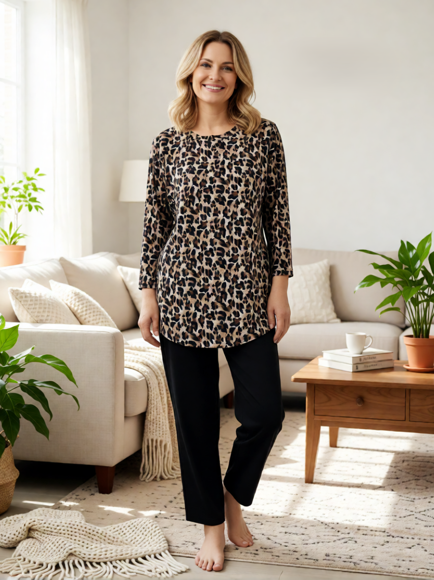 Creations' Uneven Hem Printed Hacci Top in leopard print paired with black pants in a bright living room setting.