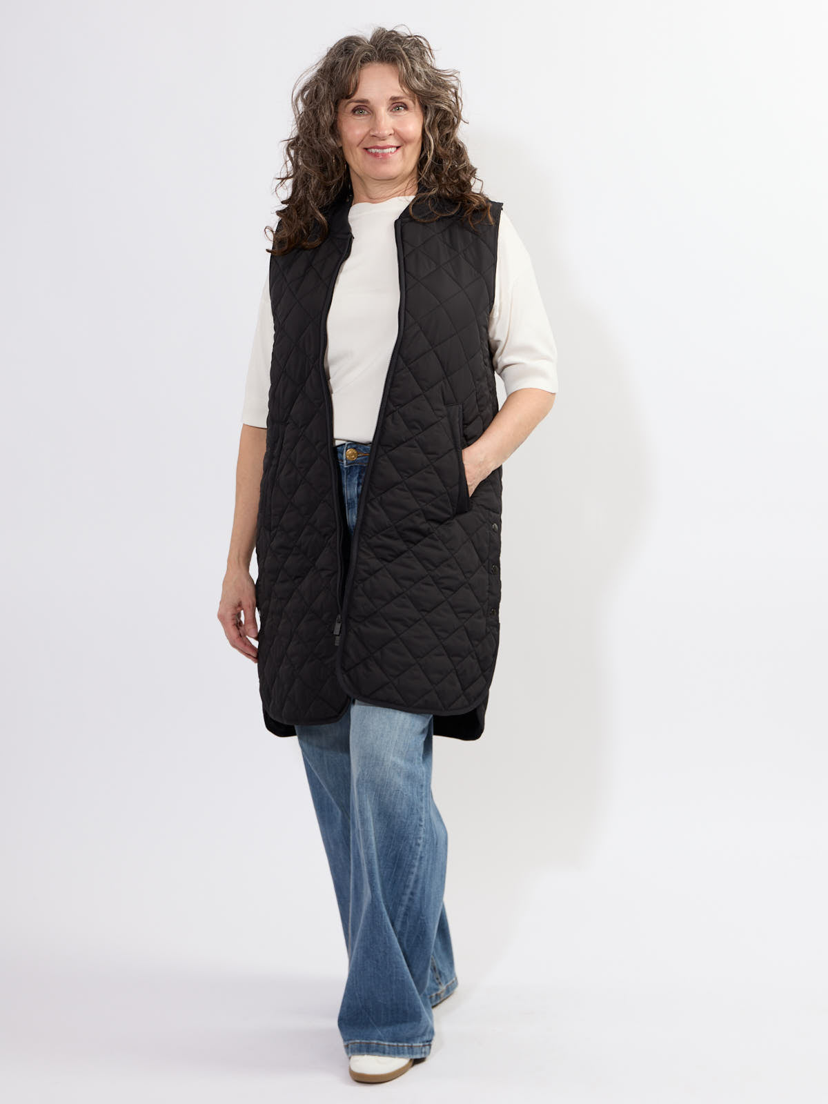 Model wearing Ilse Jacobsen Quilted Vest in black over white top and blue jeans, showcasing casual outerwear style.