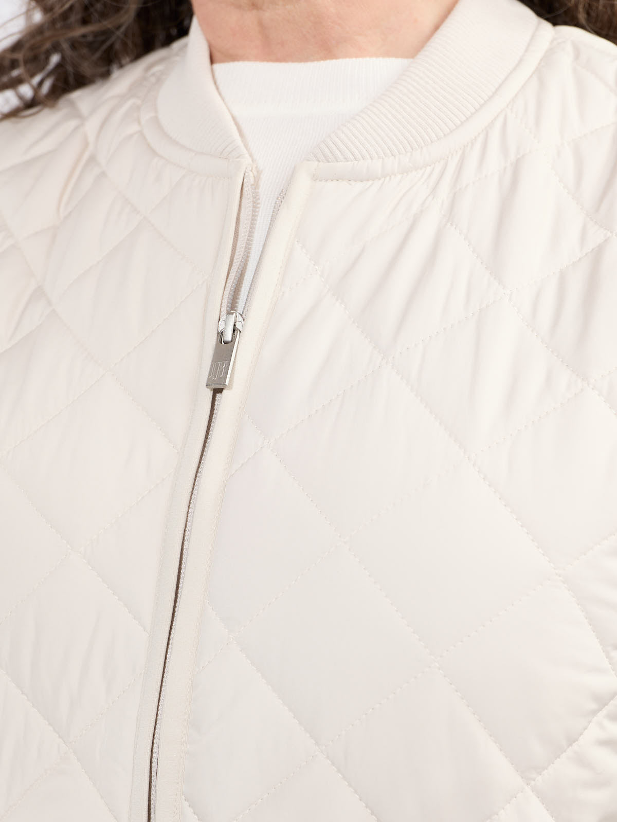 Close-up of cream quilted outerwear with ribbed collar and zipper from Ilse Jacobsen Quilted Vest collection