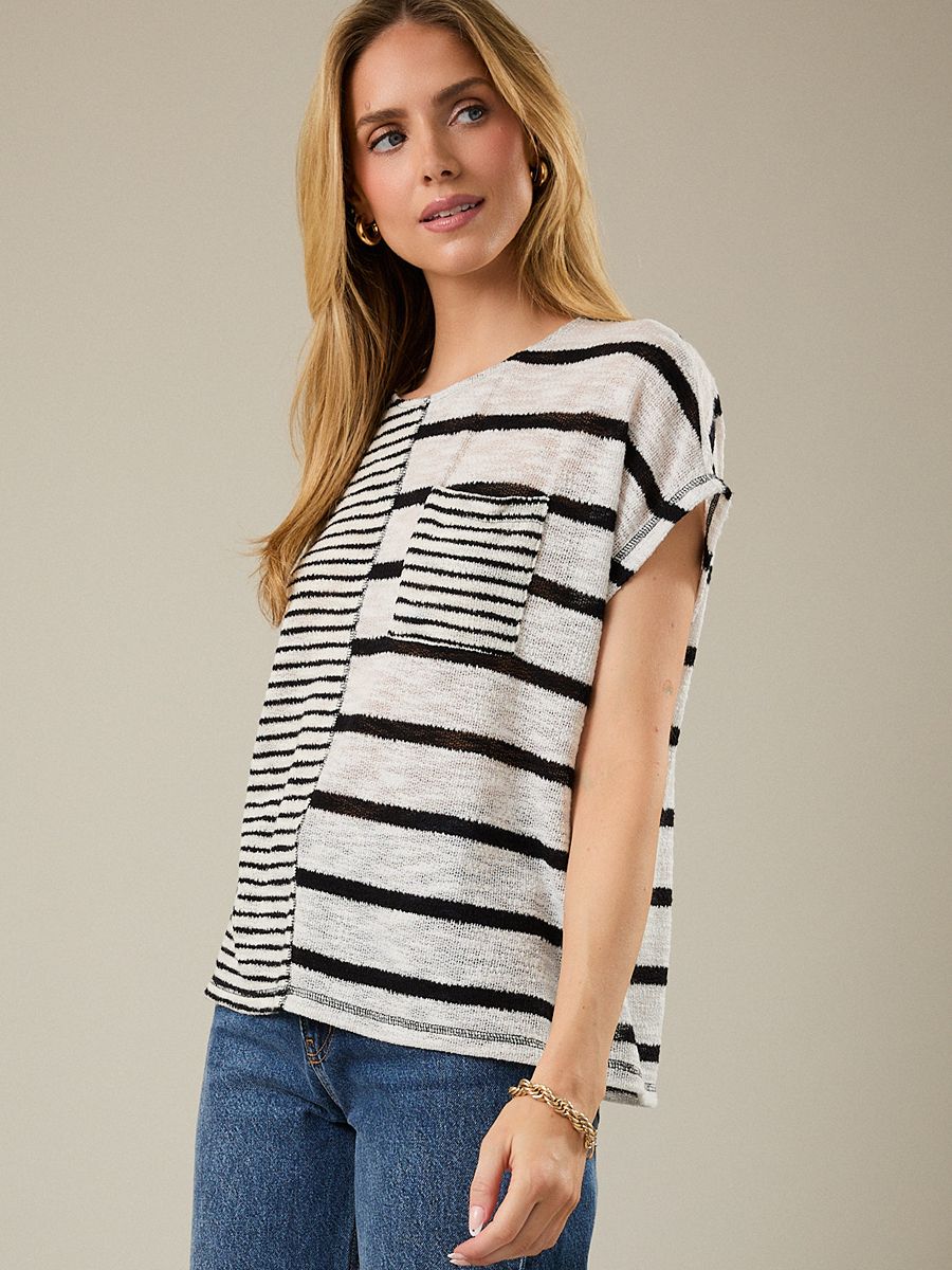 Loose short-sleeve top with mixed black and white horizontal stripes and a striped chest pocket paired with blue jeans