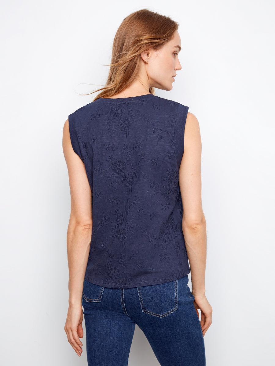 Navy sleeveless top with subtle floral texture paired with dark blue denim jeans on a person facing away