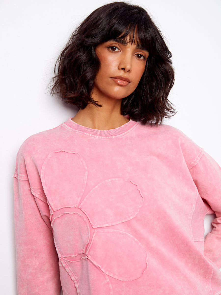 Model wears pink Charlie B Daisy Washed Terry Crew Neck Sweatshirt with large floral applique and relaxed fit sweater