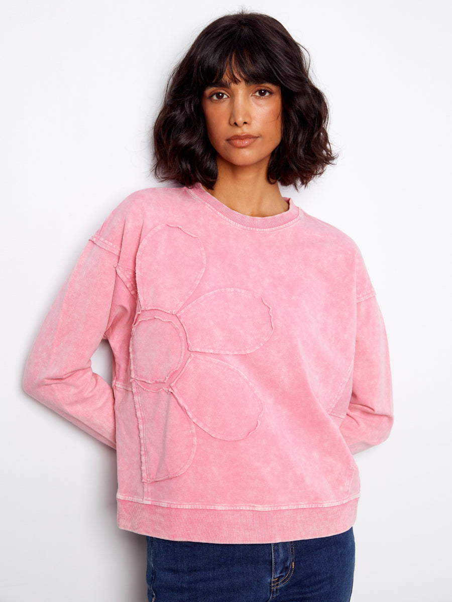 Model in a pink Charlie B Daisy Washed Terry Crew Neck Sweatshirt with subtle flower design and blue jeans