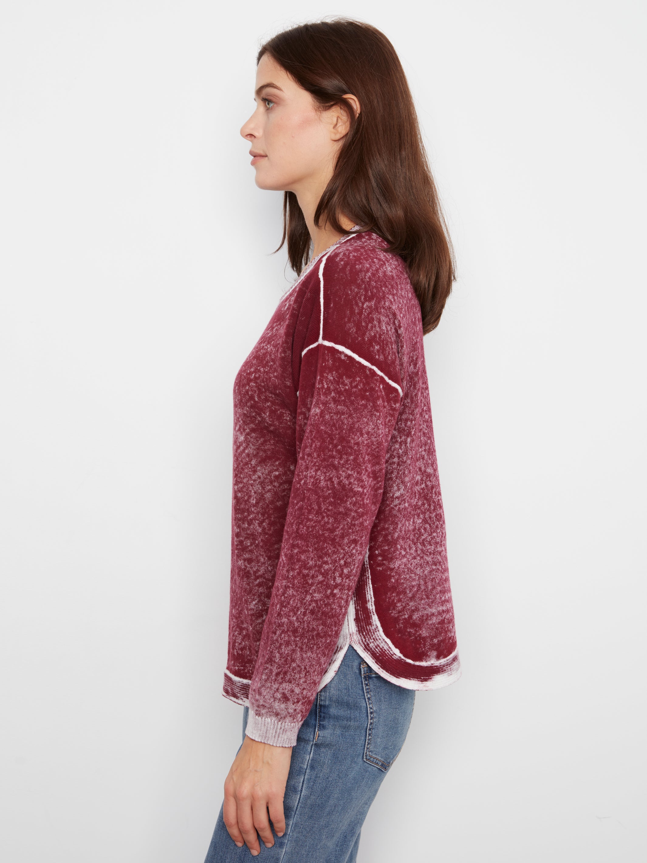 Side view of a red textured sweater with visible white seams paired with blue denim jeans against a white background.