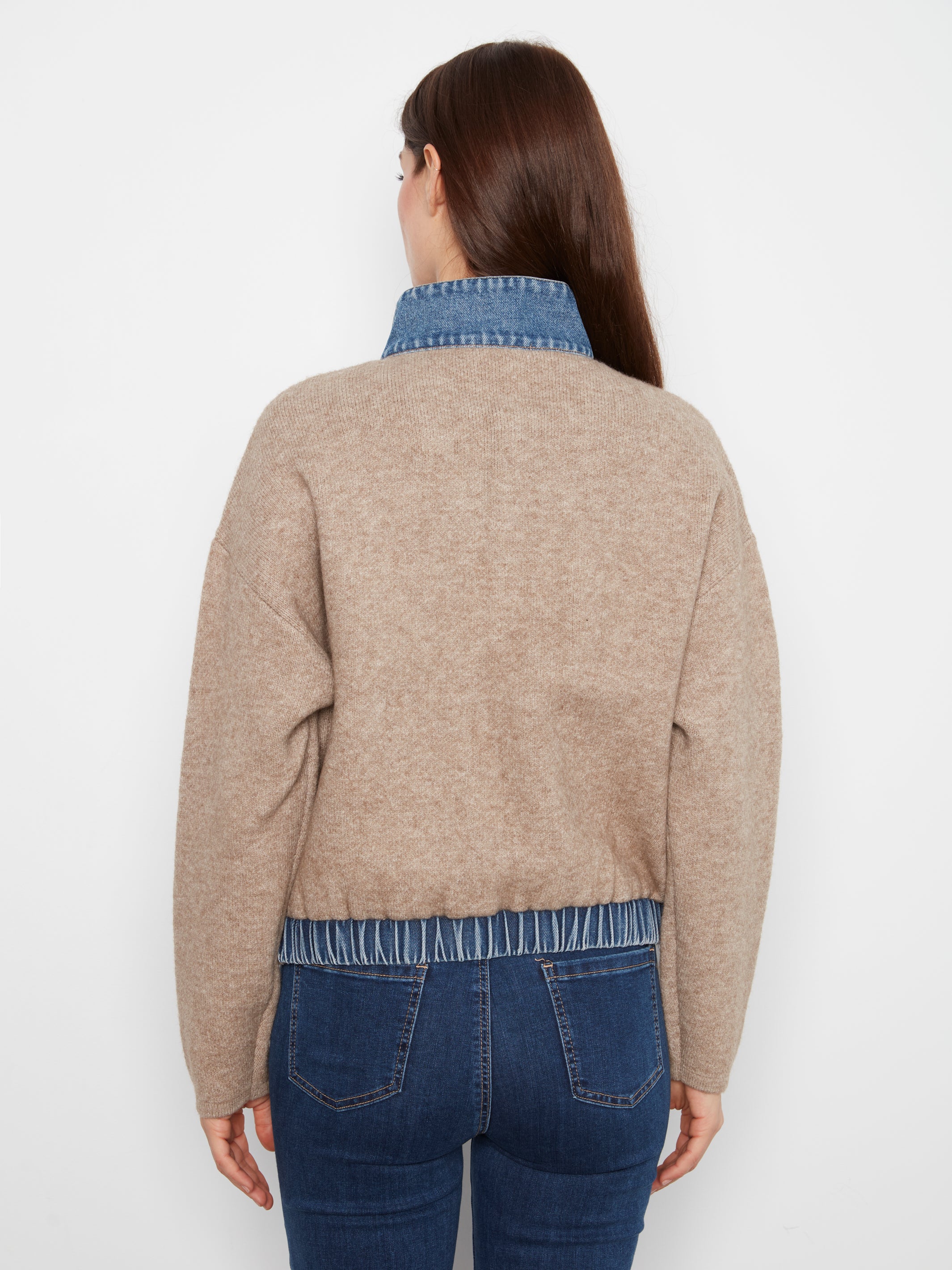 Beige knit sweater layered over a blue denim shirt with dark blue jeans, viewed from the back.