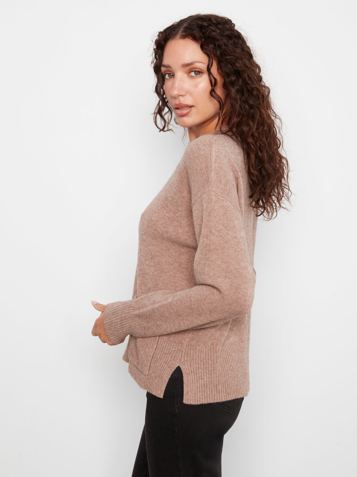 Side view of a beige Charlie B Side Pocket Plushy Rib Crew Neck Sweater paired with black pants by Charlie B