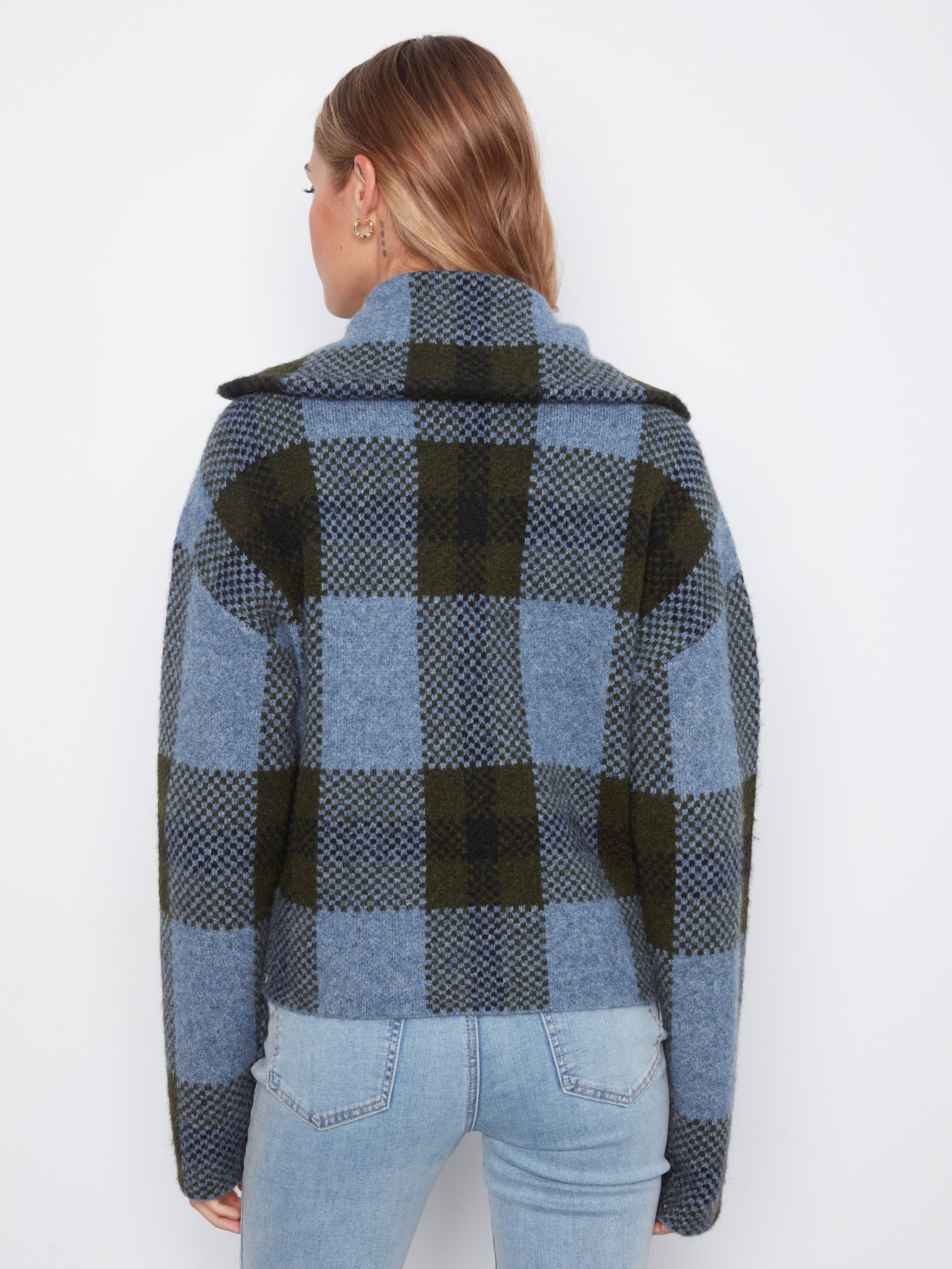 Back view of a jacket with large blue and green checkered pattern paired with light blue denim jeans.