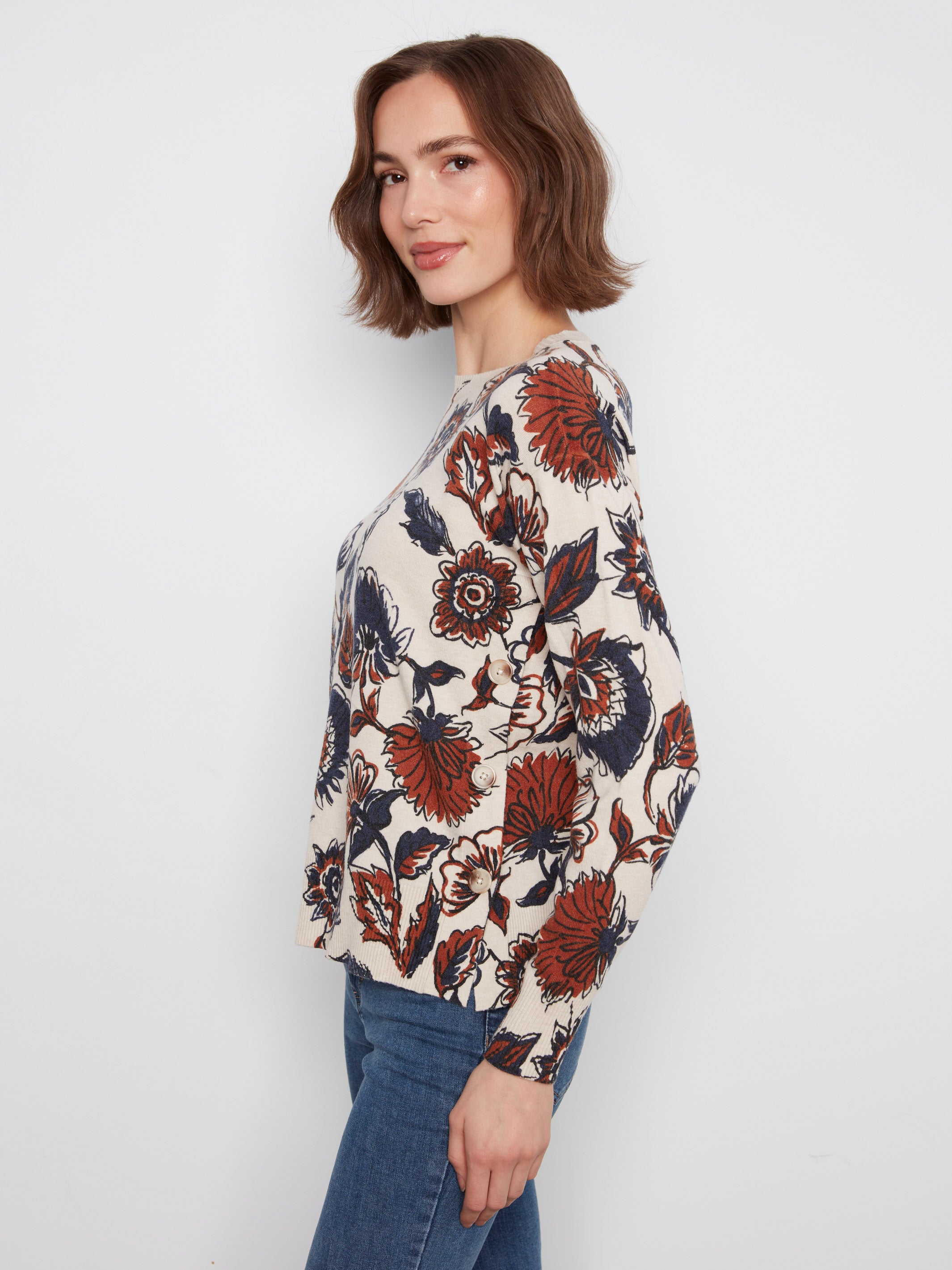 Side view of a floral patterned long-sleeve top paired with blue denim jeans against a plain background.