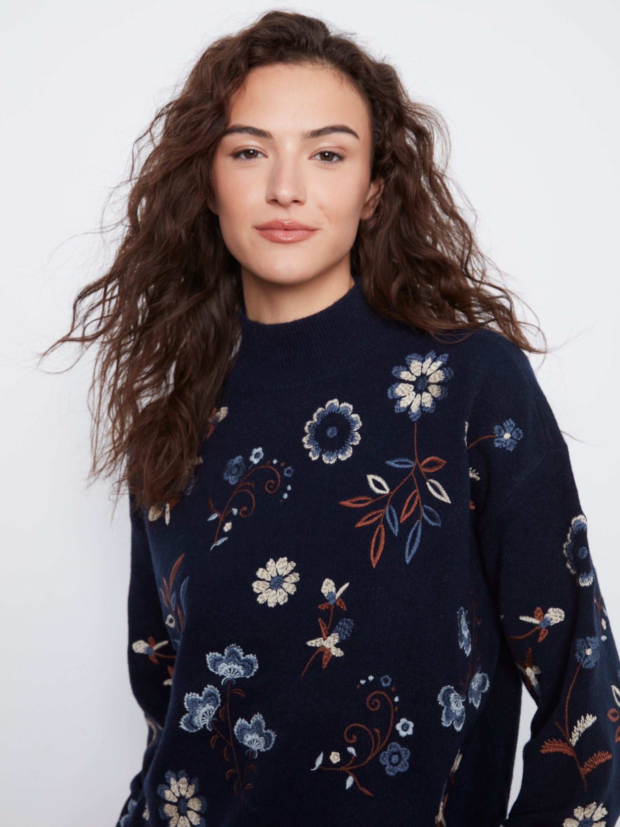 Navy blue sweater with multi-colored floral embroidery on a neutral background.