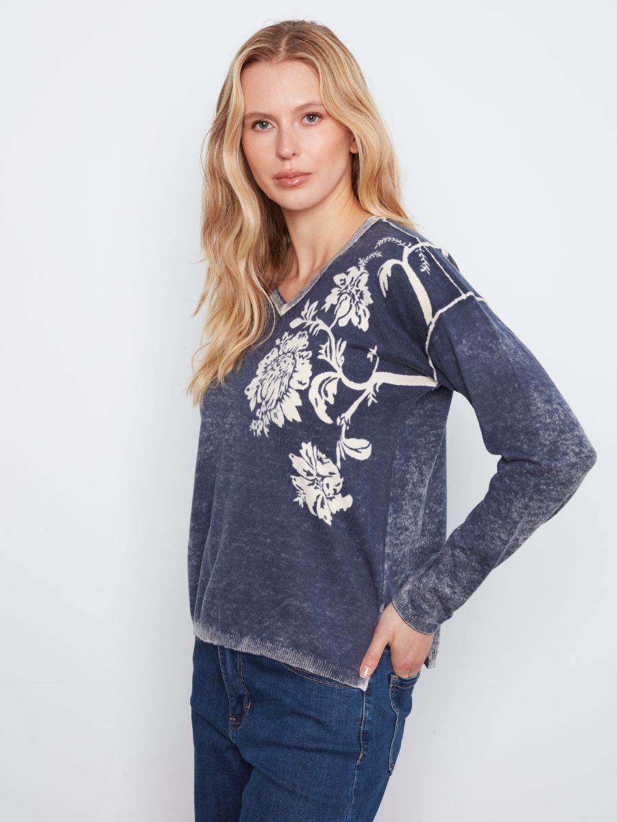 Navy long-sleeve top with white floral print and subtle faded texture paired with blue denim jeans.