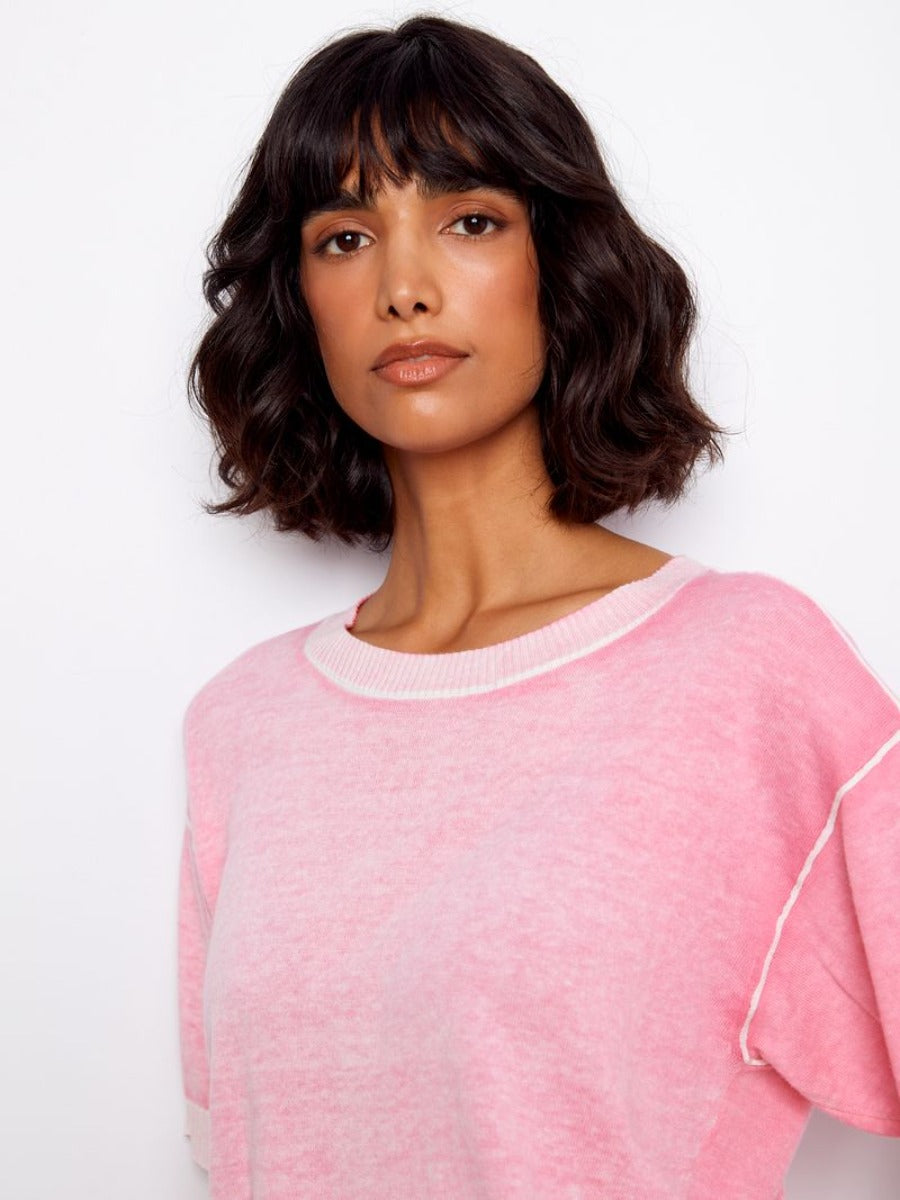 Close-up of a person wearing a pink Charlie B Skylar Washed Cotton V-Neck Sweater from Charlie B collection
