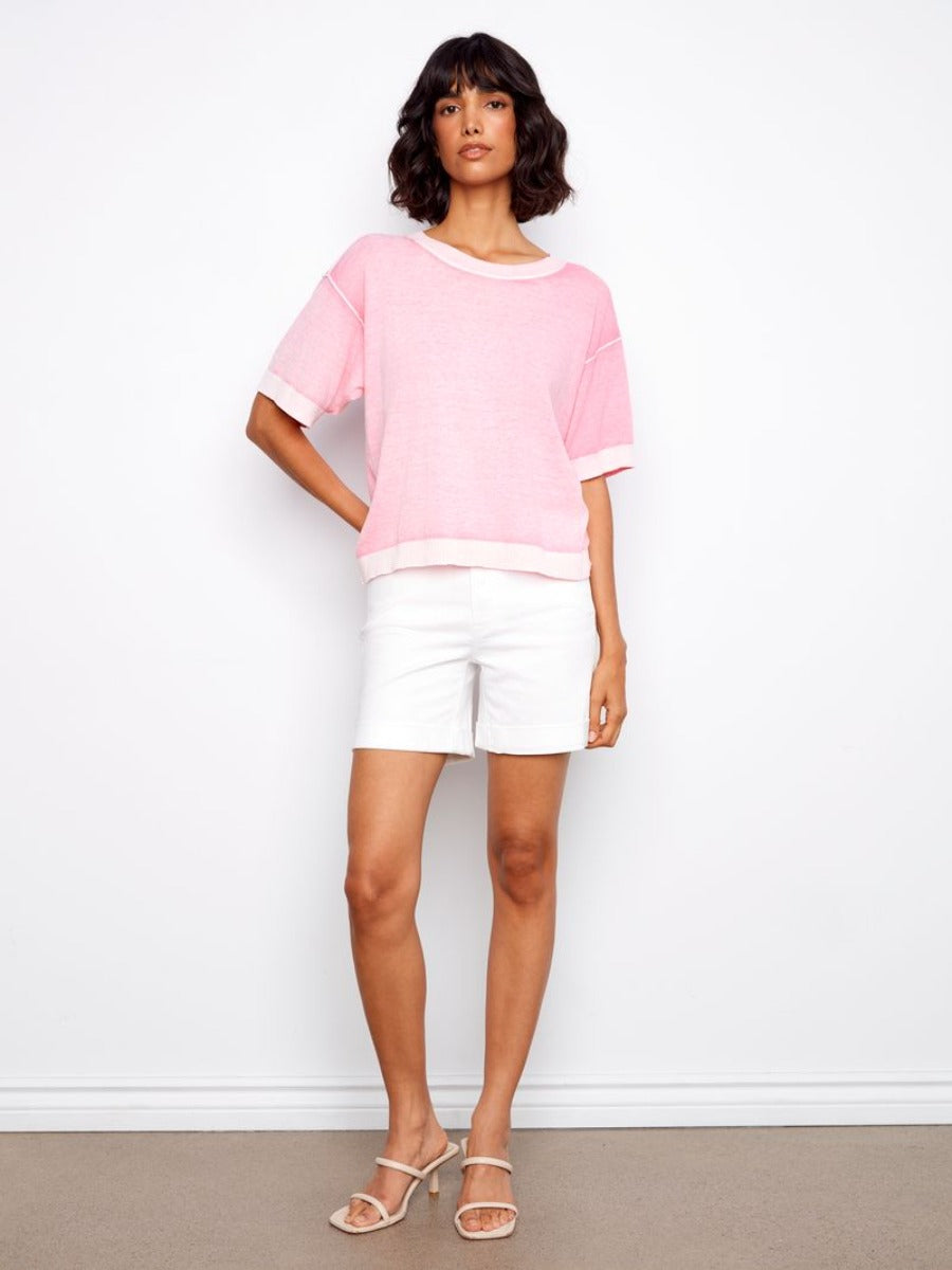 Model wears Charlie B Skylar Washed Cotton V-Neck Sweater in soft pink by Charlie B paired with white shorts and sandals.