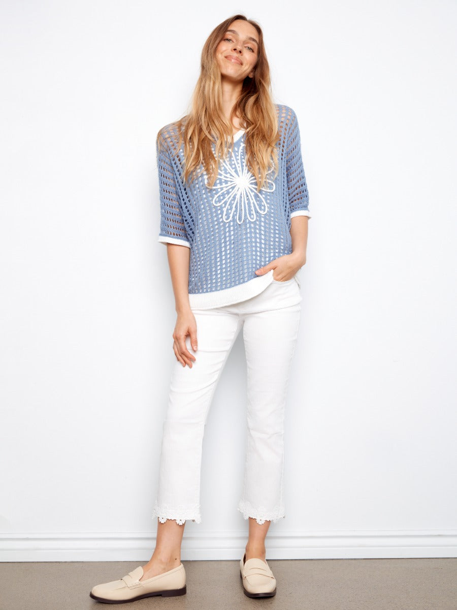 Charlie B Daisy Crochet Sleeveless V-Neck Top in blue crochet with white floral design, styled with white pants by Charlie B.