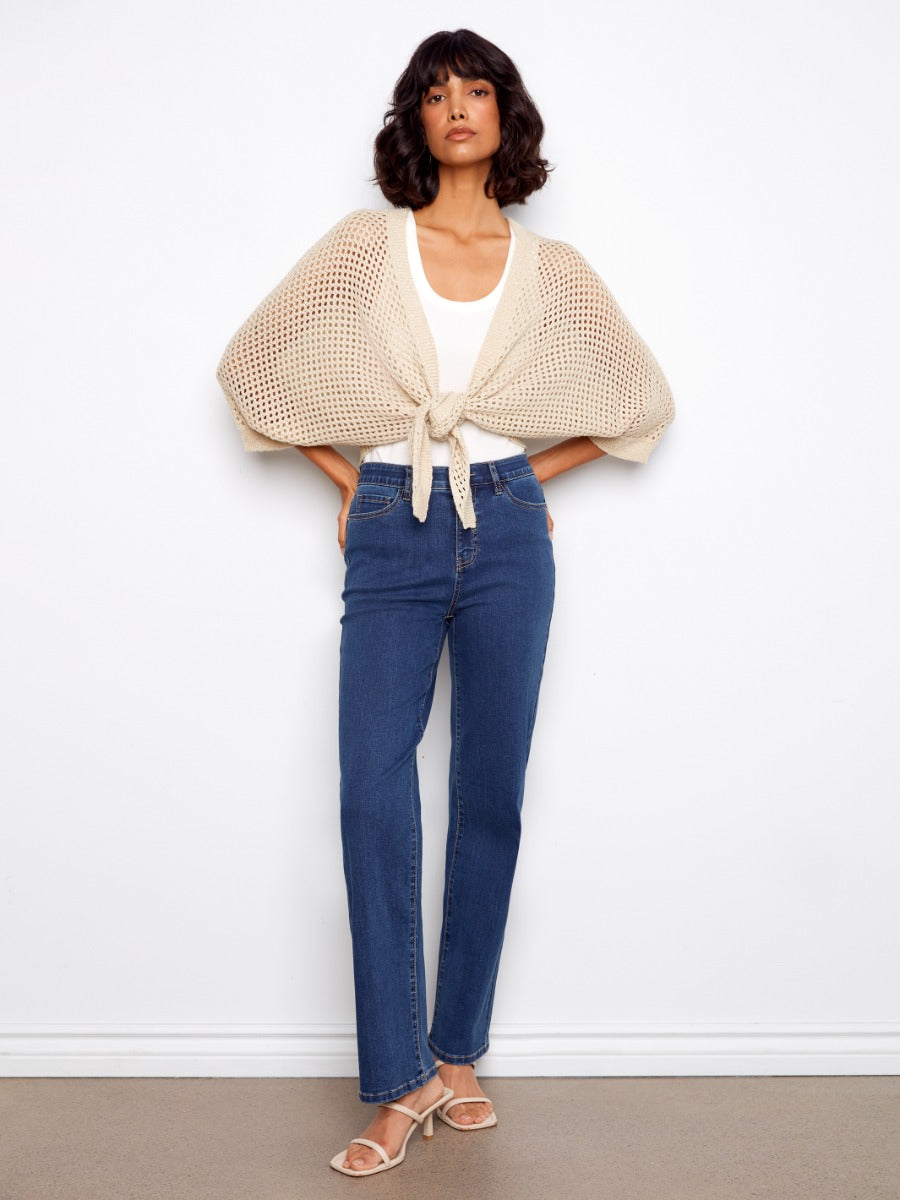Charlie B Open Front Sleeveless Crochet Cardigan in beige knit, styled with denim jeans and sandals, designed by Charlie B.