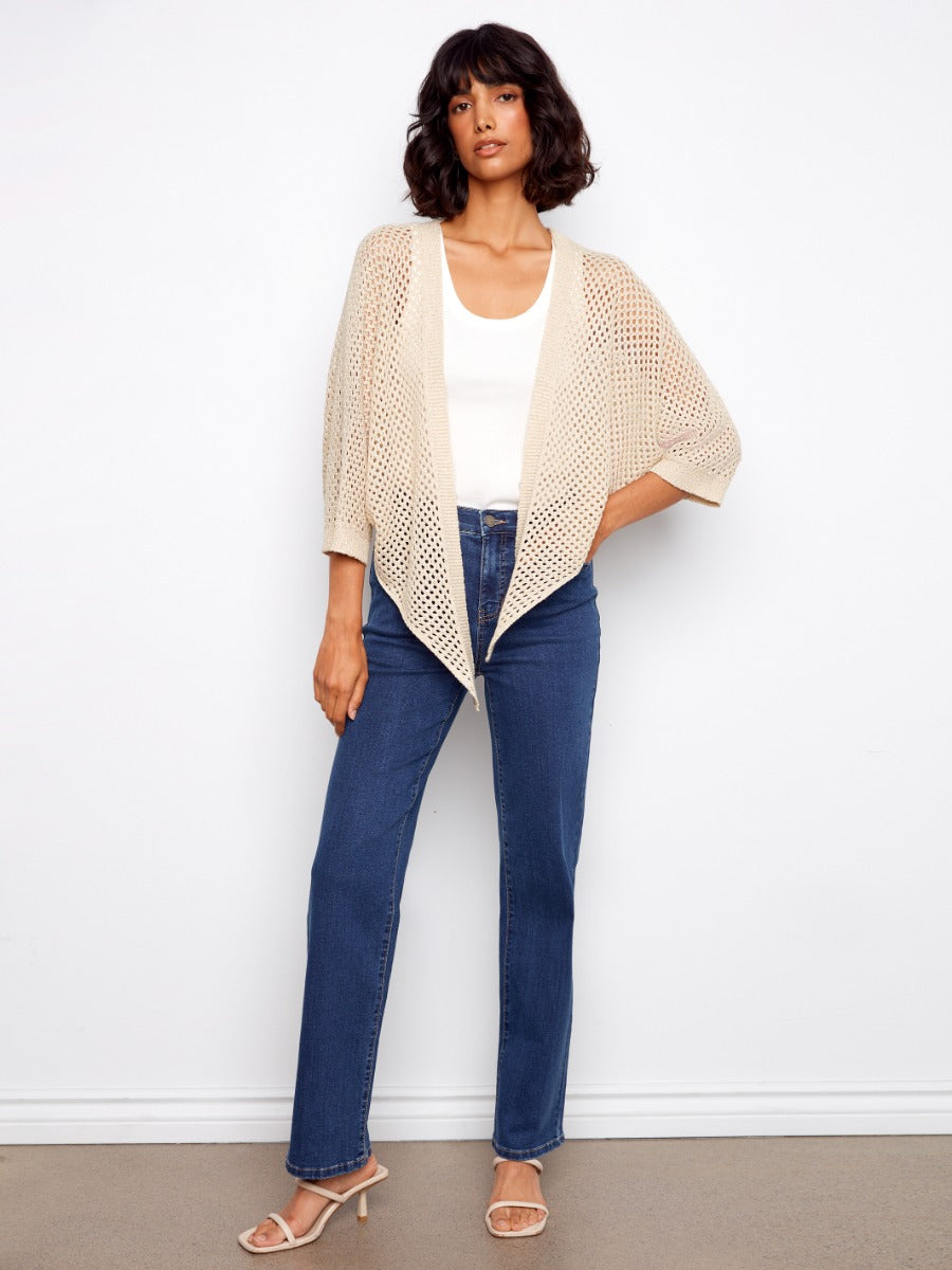Charlie B Open Front Sleeveless Crochet Cardigan in beige, styled over white top and denim jeans by Charlie B.