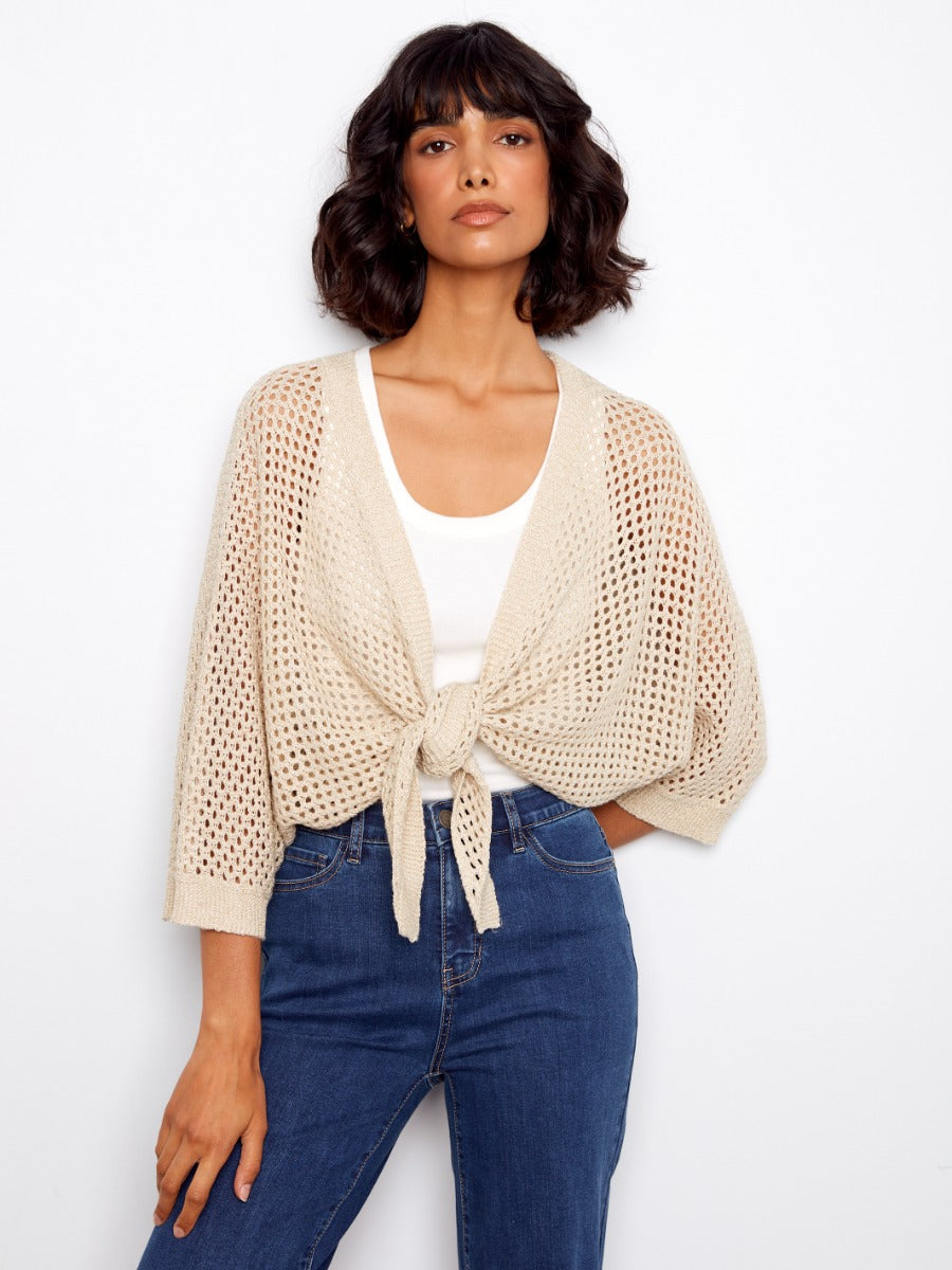 Charlie B Open Front Sleeveless Crochet Cardigan in beige knit, tied front detail, styled with white top and blue denim jeans.