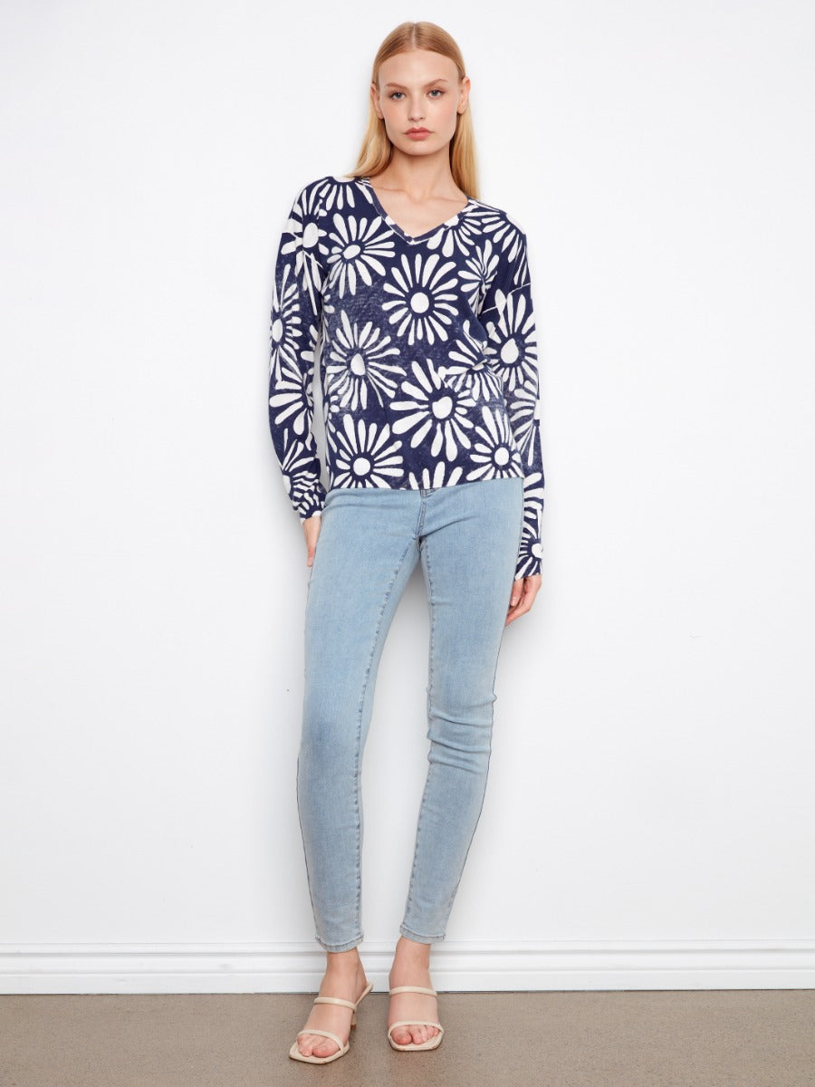 Charlie B Suns Out Ribbed Cotton V-Neck Sweater in navy with white floral pattern, paired with light denim jeans.