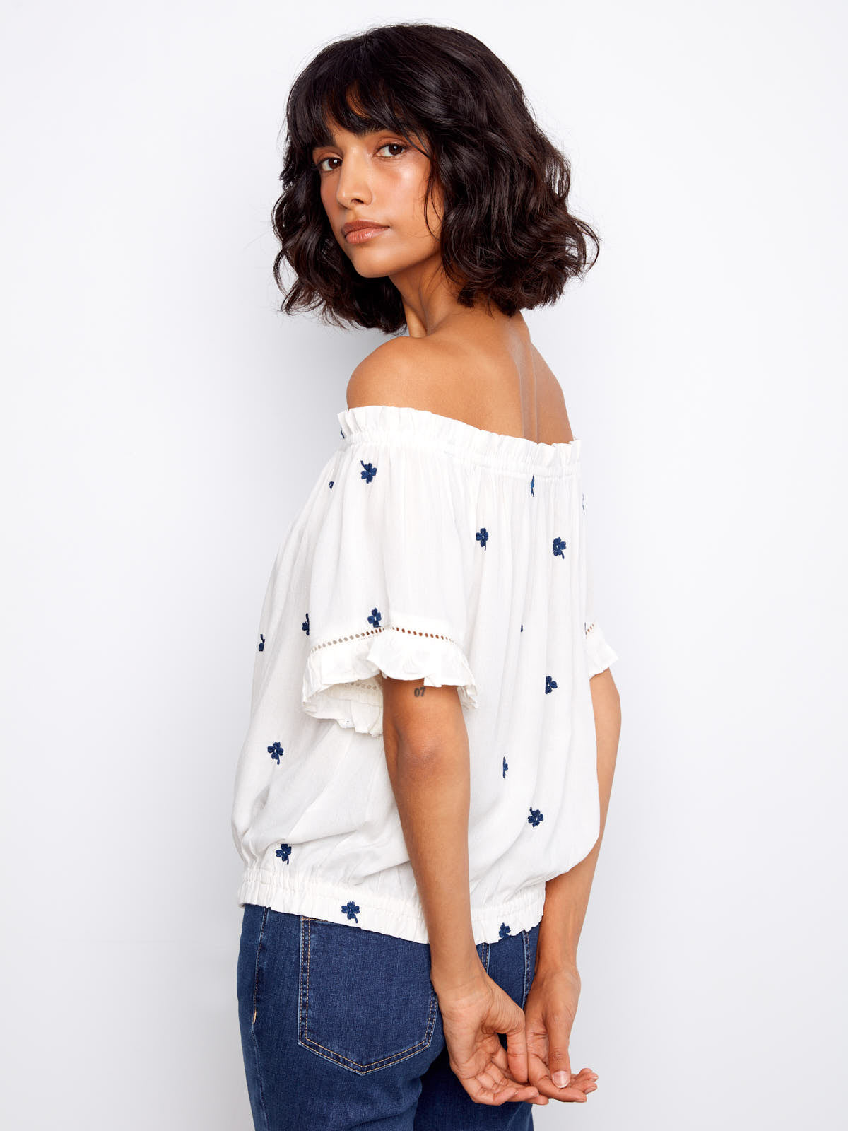 Model showcasing Charlie B Embroidered Clover Short Sleeve Top in white with navy clover embroidery and denim jeans by Charlie B