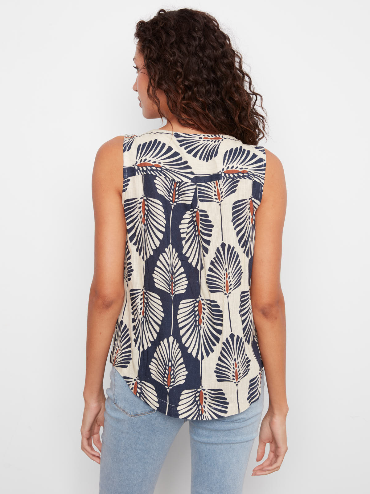 Back view of Charlie B Tahiti Linen Sleeveless Top in navy and beige leaf pattern with light blue jeans.