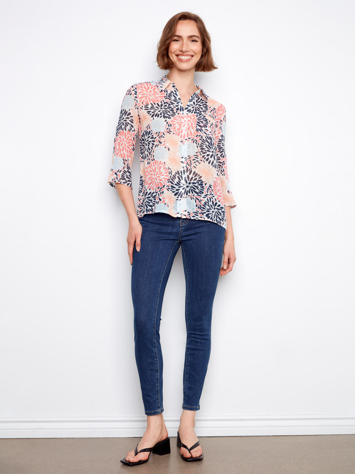 Charlie B Johanna Gauze Roll Sleeve Top in multicolor floral pattern paired with blue jeans and black sandals