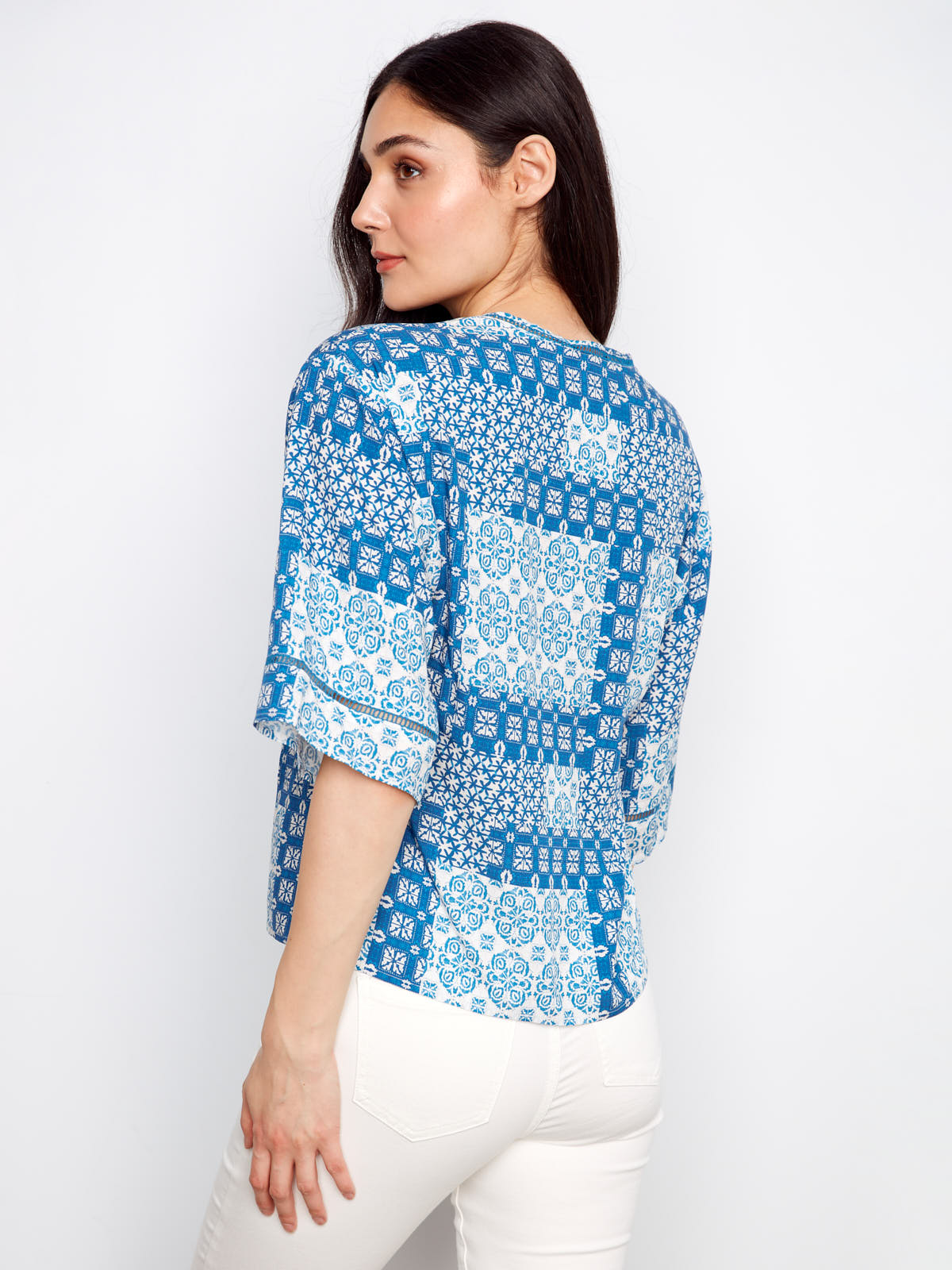 Back view of Charlie B Patchwork ¾ Sleeve Top in blue patterned fabric styled with white pants by Charlie B.