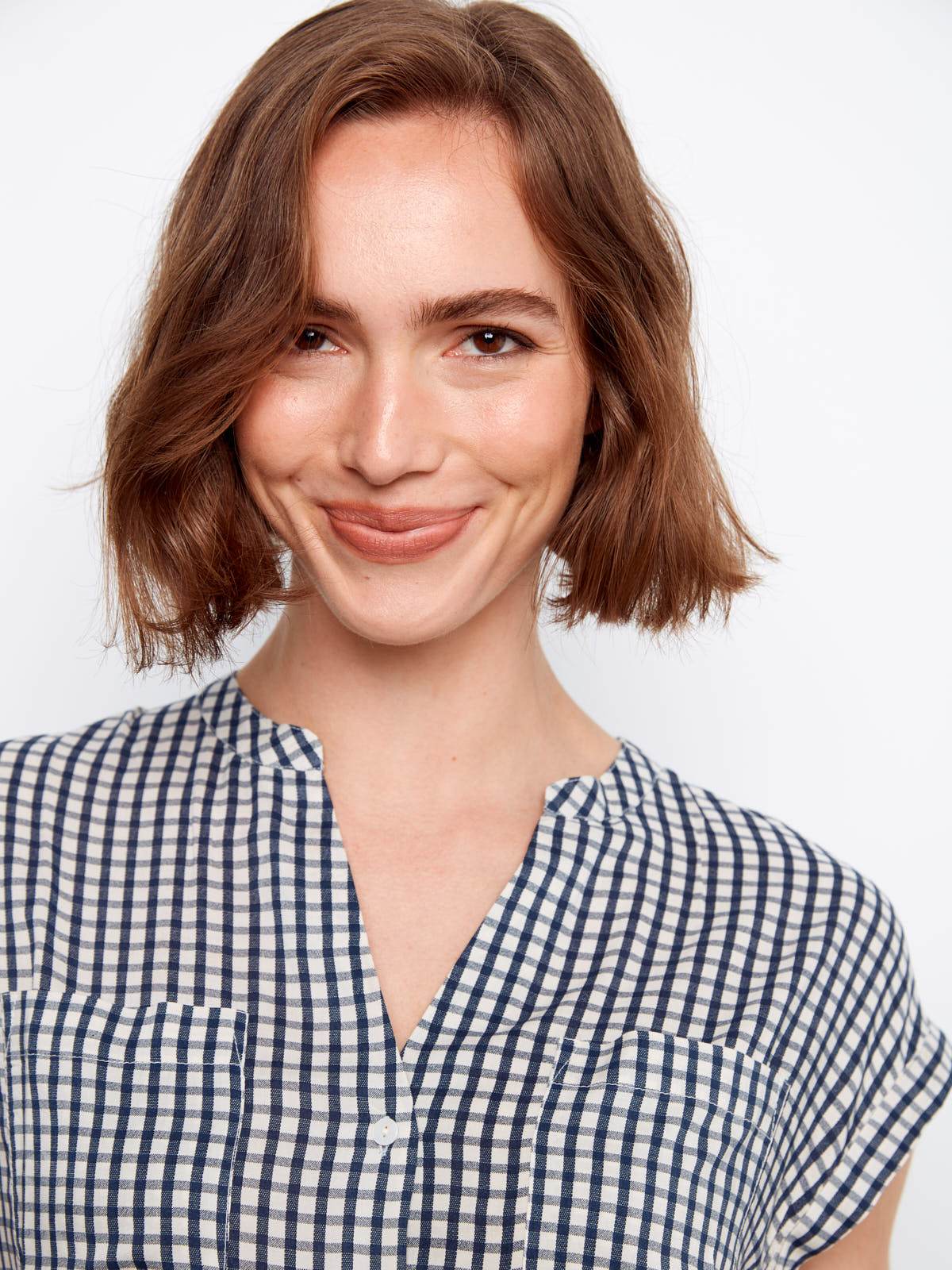 Close-up of a smiling person wearing a navy and white checkered Charlie B Nautical Gingham Button Front Top by Charlie B