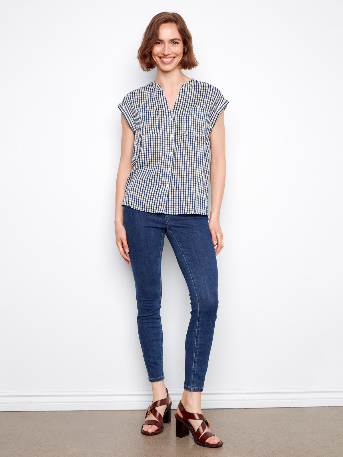 Model wearing Charlie B Nautical Gingham Button Front Top by Charlie B paired with blue denim jeans and brown sandals
