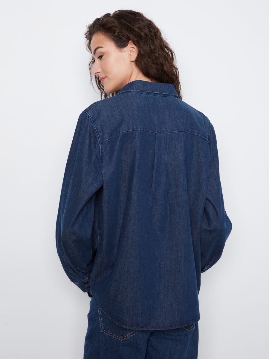 Dark indigo denim long-sleeve shirt with seam detailing on the back, worn over matching denim pants.