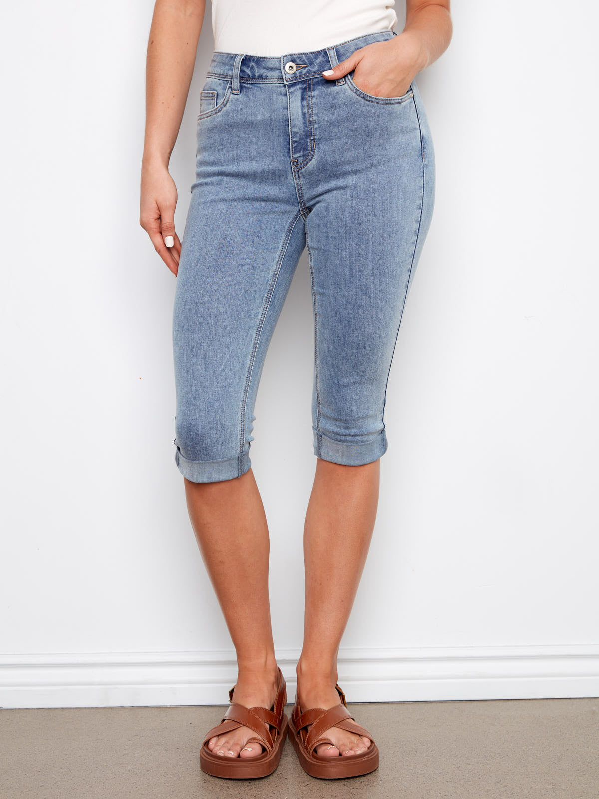 Charlie B Pedal Pusher 17” Denim Short in light blue denim with rolled hems from Charlie B, styled with brown sandals.