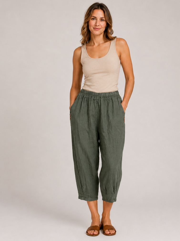 Slim fit beige tank top paired with loose olive green cropped pants and brown slide sandals against plain background.