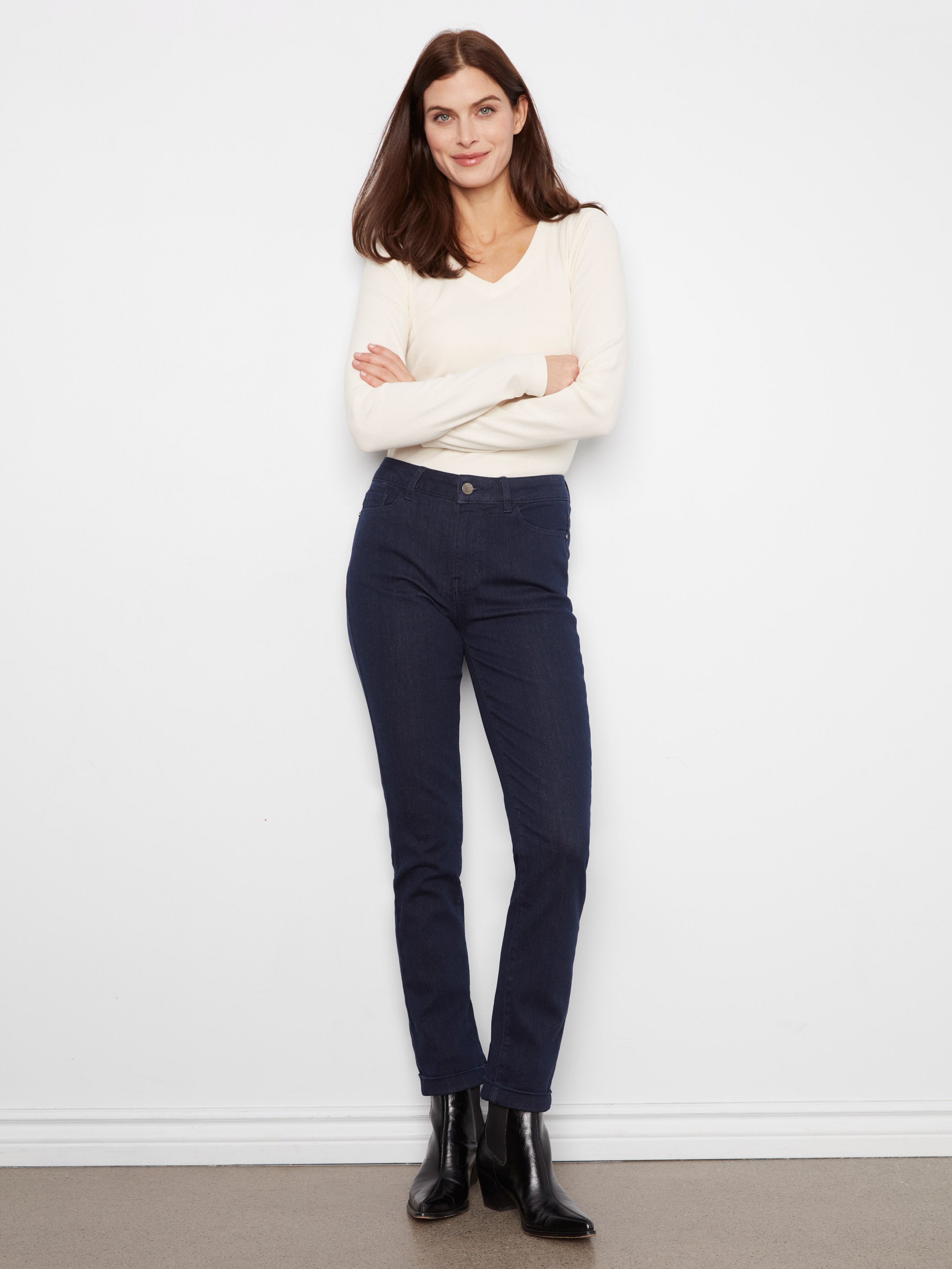 Light cream long-sleeve top paired with dark navy straight-leg pants and black ankle boots against a white background.