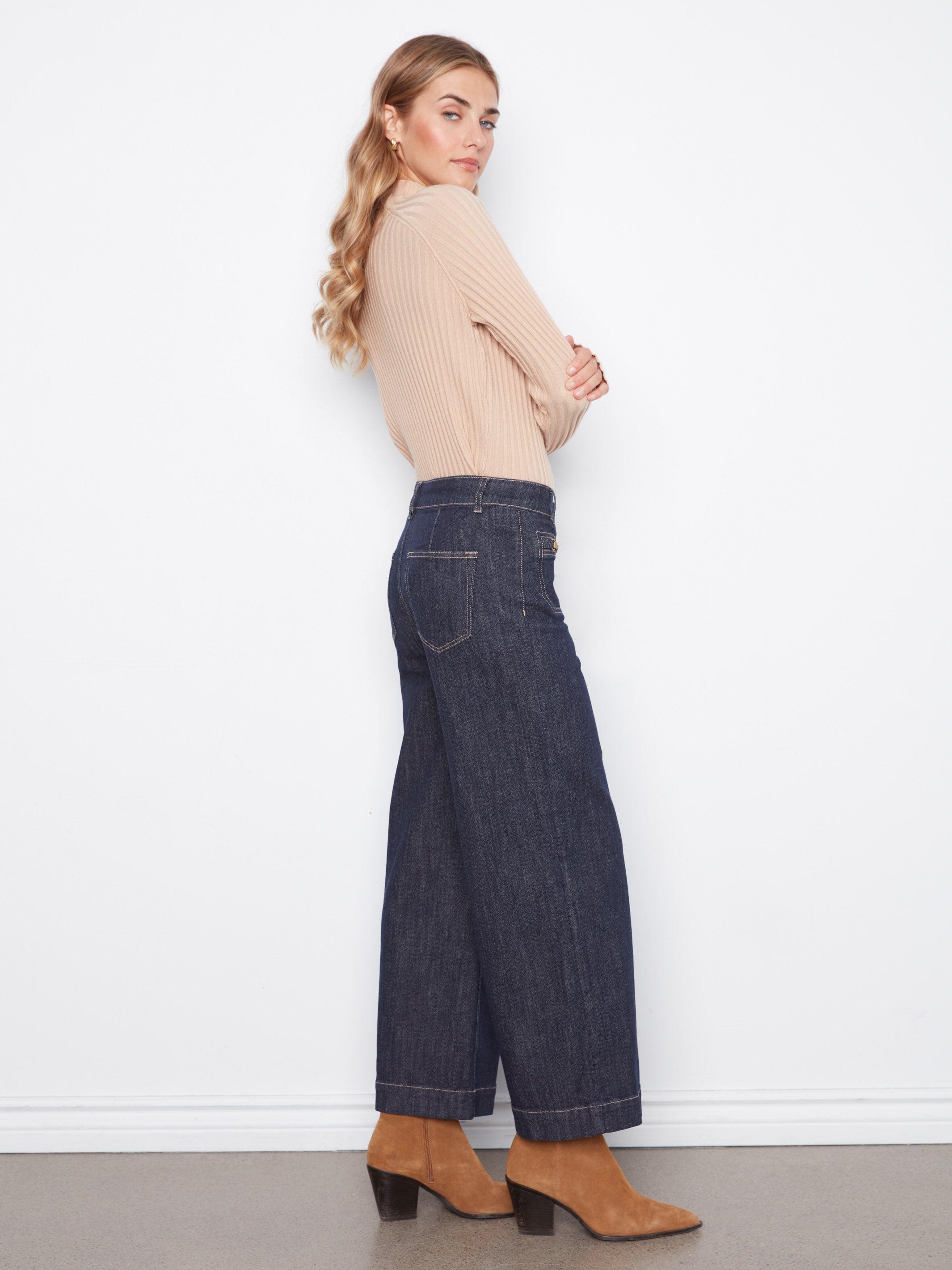 Side view of beige ribbed long-sleeve top paired with wide-leg dark denim jeans and tan suede boots.
