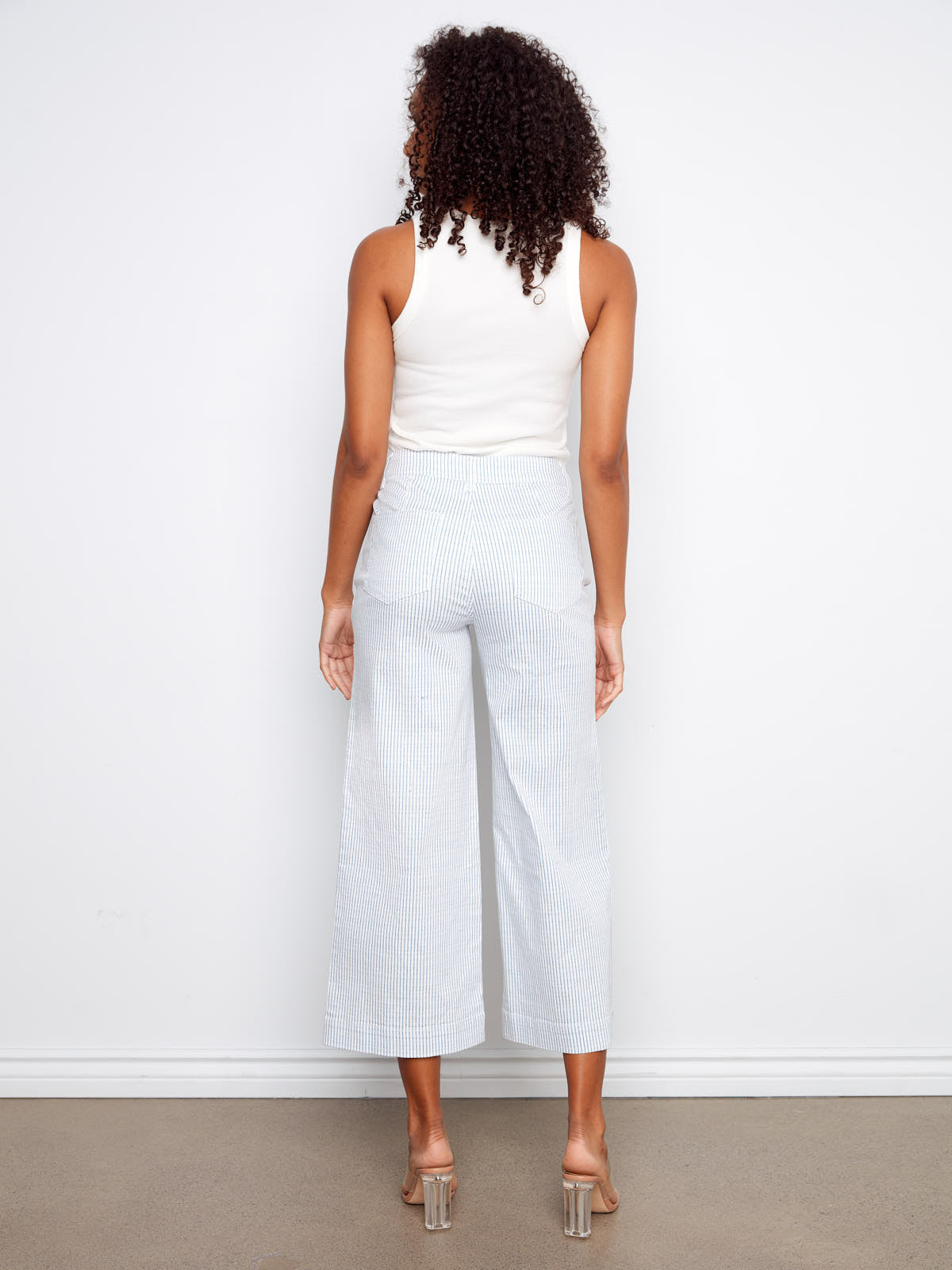 Back view of Charlie B Double Trouble Lines Flare Jean in light striped denim by Charlie B with clear heels.
