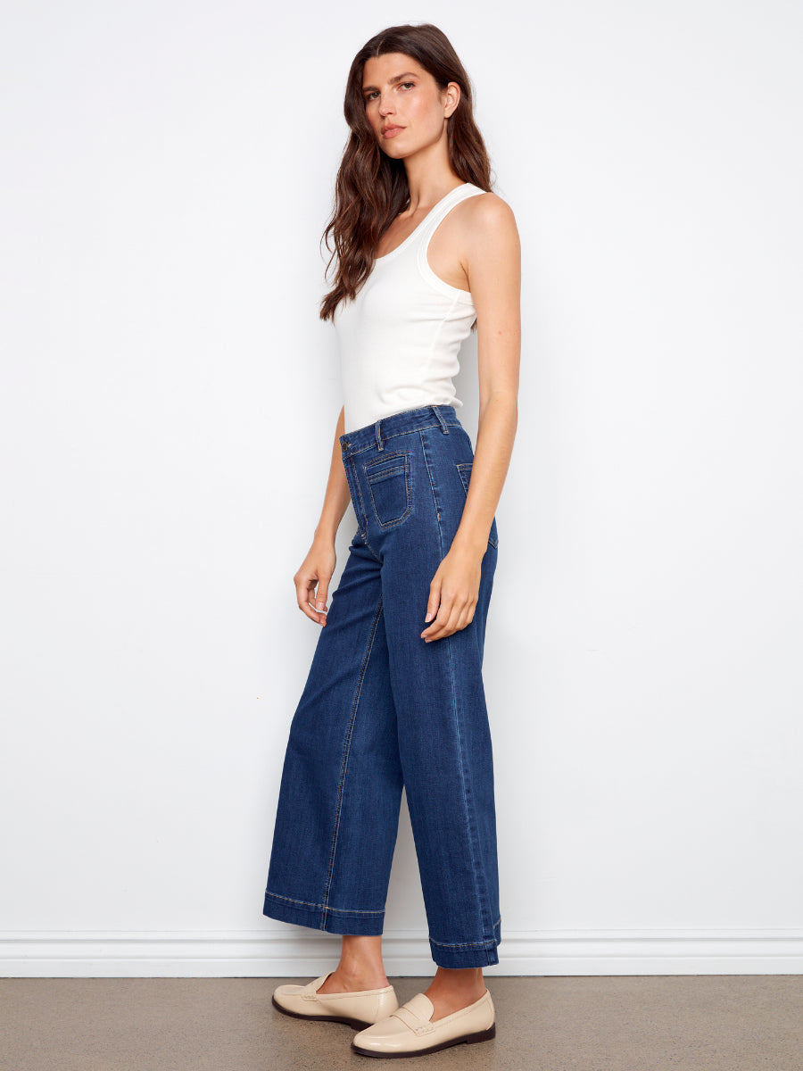 Model in white tank top wearing Charlie B Double Trouble High Rise Flared Denim Jeans in dark blue by Charlie B
