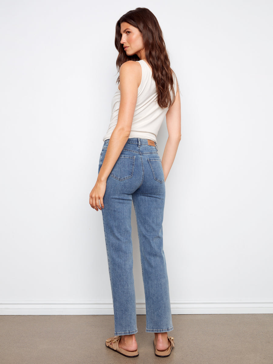 Model wearing Charlie B Charlotte Straight Leg Denim Jeans in medium blue styled with a sleeveless white top and sandals
