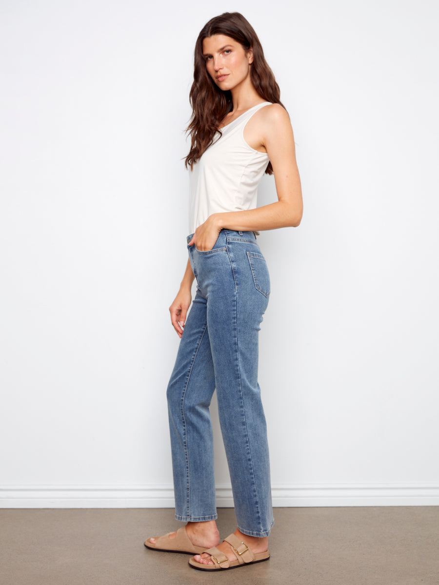 Model in Charlie B Charlotte Straight Leg Denim Jeans with white tank top and sandals on neutral background