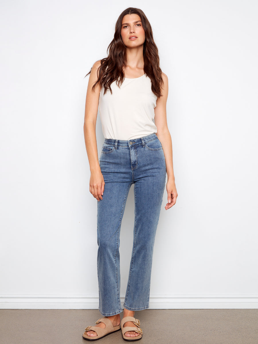 Slim fit Charlie B Charlotte Straight Leg Denim Jeans in medium blue paired with a white tank top and sandals