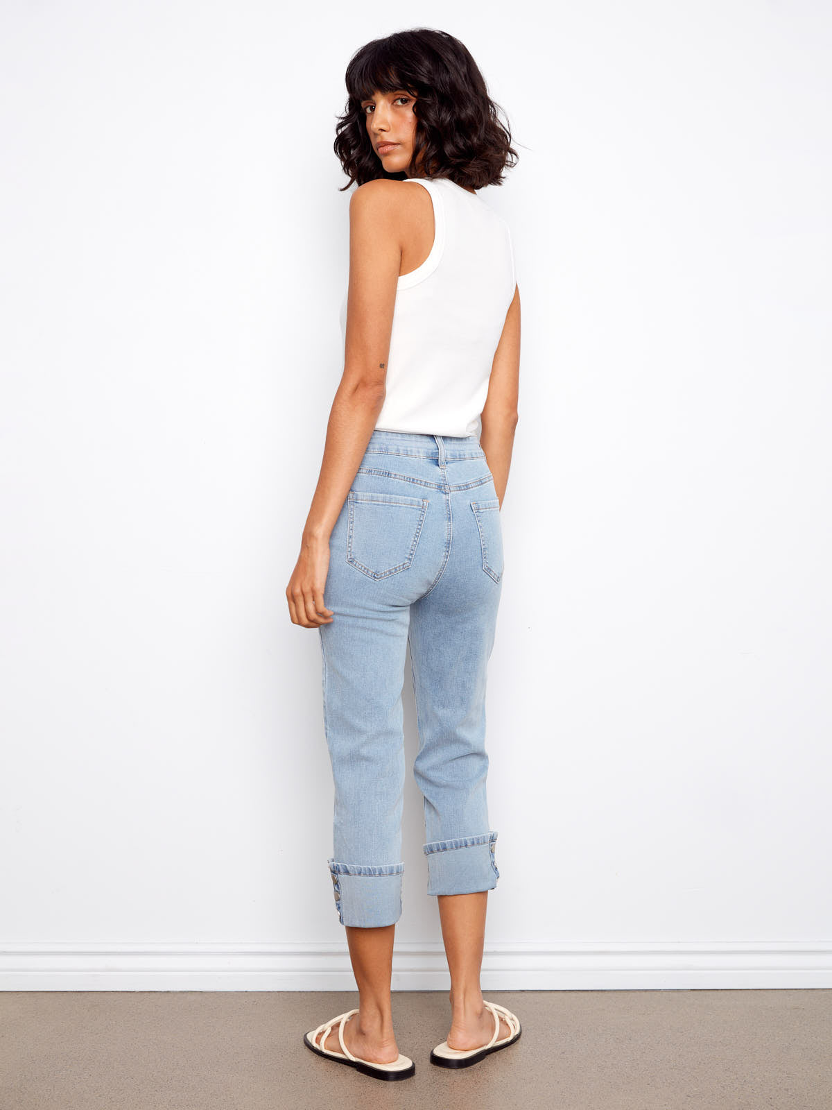Light blue denim Charlie B Up Down Snap 26” Cropped Denim Capris with snap cuffs paired with a white sleeveless top