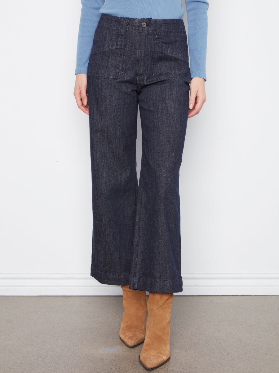 Dark denim wide-leg pants with front pockets paired with tan suede ankle boots and a light blue long-sleeve top.